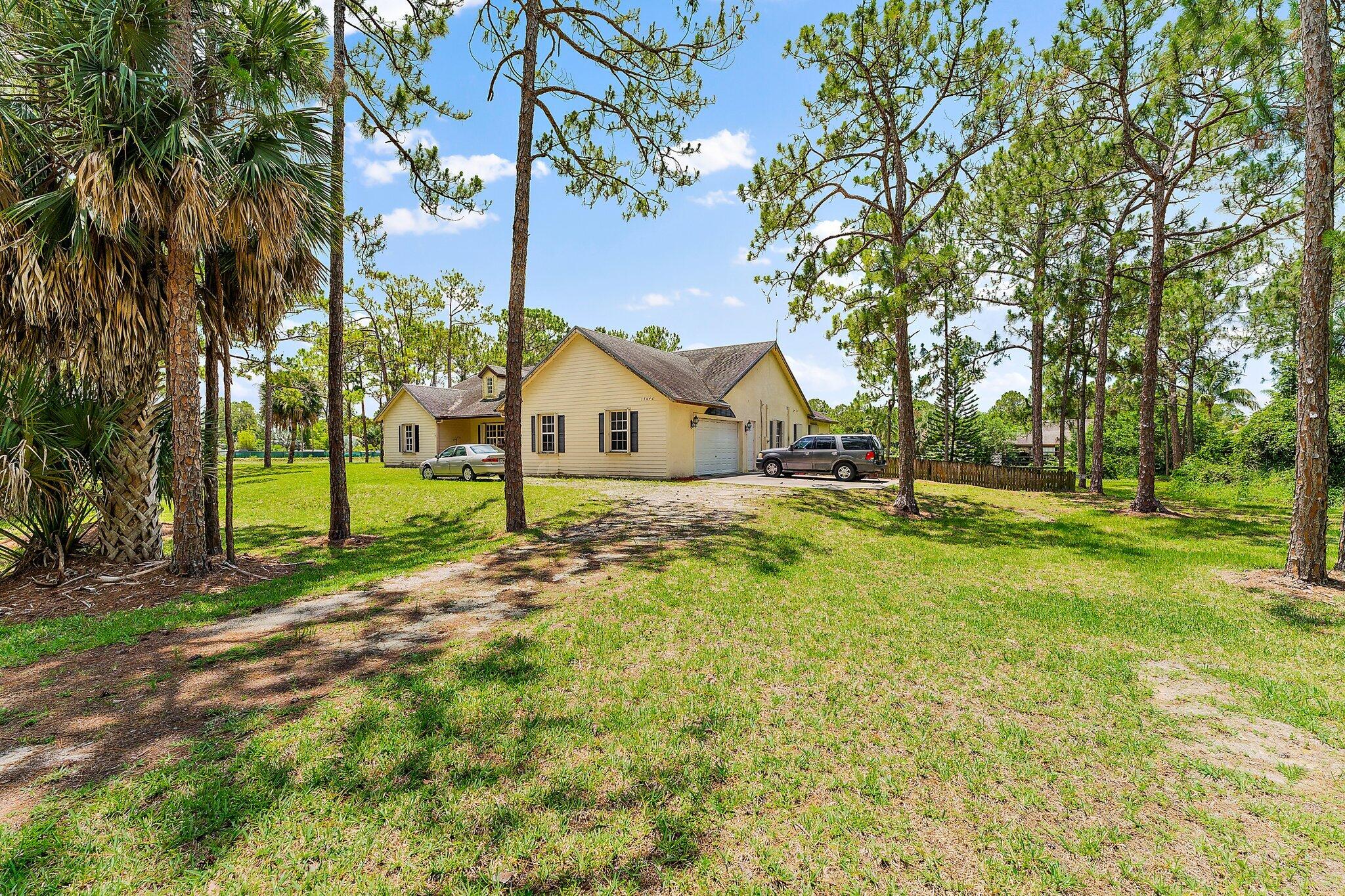 CONCRETE HOME on 2.49 acres w/ custom Spacious 3000 sq ft Ranch Home in desirable Loxahatchee Florida! This home sits privately at the end of 73rd on a wooded & corner lot on a canal where you can relax in peace & fish for bass, tilapia. This motivated seller built this home built in 2002 & it has all the items you would think of full shutters, central vacuum, inside laundry room, walk in closets, huge pantry, vaulted & tray ceilings, large spacious bedrooms, living space & kitchen with lots of storage thru-out & walk ins. The custom bell tower & dormer windows have lighting for ambience.  There are 3 large bathrooms and 2 en-suites, one is used for owners suite & the other is used for in-law suite. Both of these suites have their own temperature control & exit to screened back patio >>>