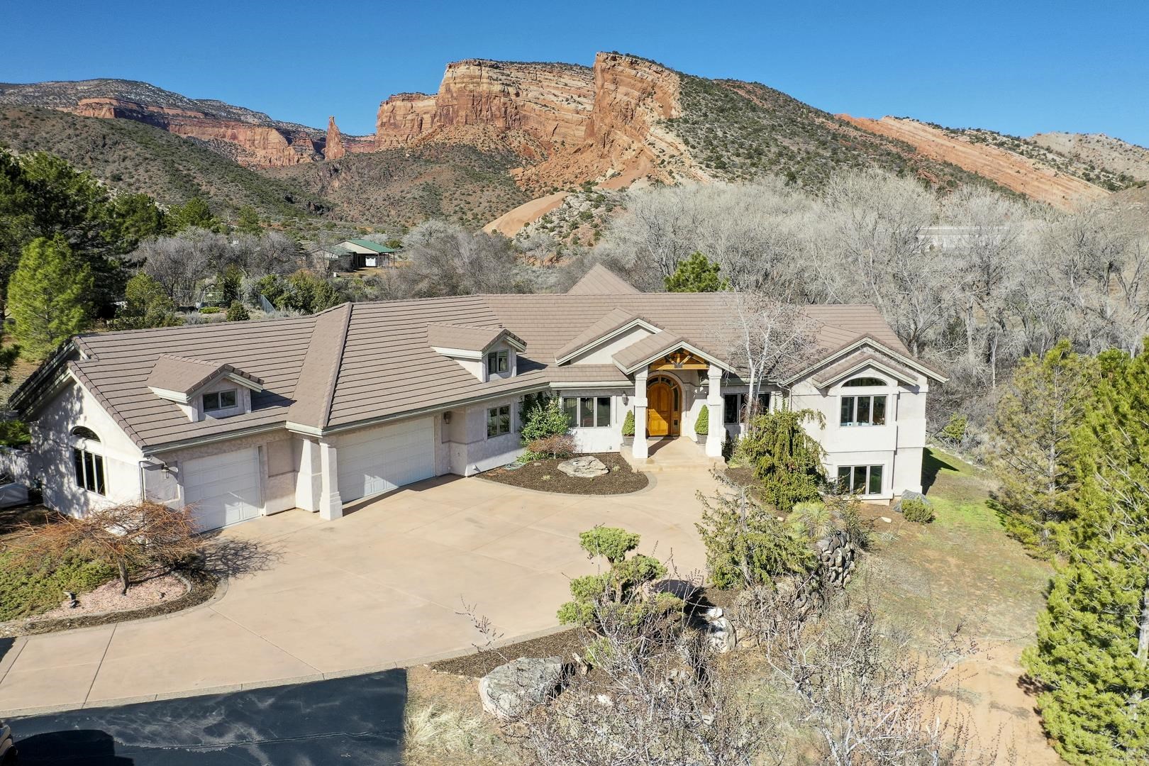 Situated at the base of the Colorado National Monument w/epic views of Independence Rock! This home was designed to feature Independence Rock & the National Monument like no other home you'll see & you'll know the second you walk through the front door! Designed w/dramatic 3 story wall of windows that is 30 feet wide which creates an incredible effect, similar to living wall paper. No 2 days will ever appear the same from this incredible home! The master & office are on main floor & down stairs you'll find 2 more bedrooms w/family room & wet bar. Master suite is incredible & features not only a luxury bath w/walk in closet, but private balcony where you can enjoy the views & watching wildlife that moseys by. Located down private drive w /over 5000 square feet, 3 bedrooms + office, 4 baths, 3 car garage w/plenty of RV parking & nice enclosed back yard!!