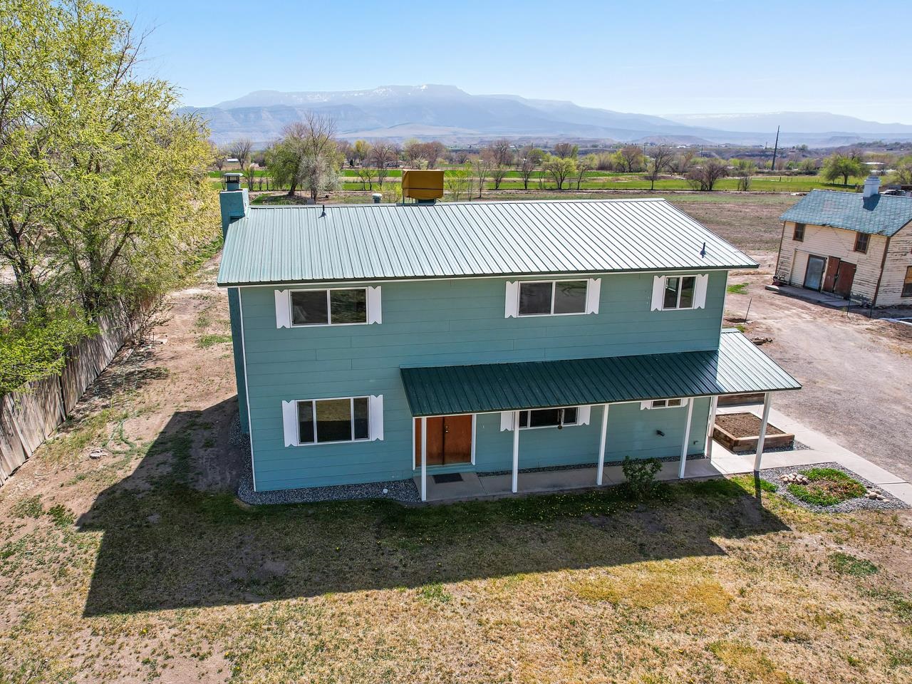 What a unique property with a nicely updated home on nearly 5 acres of land with irrigation! This area is zoned Residential Multi-Family and AFT, so could potentially be subdivided and built on. The views of the Grand Mesa, Uncompahgre Plateau, and Mt Garfield are incredible from this Grand Valley property. Tucked off 33 Rd, this home has an incredible amount of room inside and plenty of update throughout! Close to schools, amenities, Grand Junction, Clifton, and Palisade, there is plenty to do in the local area. As for the existing home, downstairs you'll find the main living spaces with a stunning brick fireplace, updated bathroom and a bedroom. The vinyl plank flooring was just installed and looks fantastic, and both a new front door and sliding glass door will be installed this month. Upstairs you’ll find three conforming bedrooms and two additional rooms that could be non-conforming bedrooms or bonus living spaces as well as an additional updated bathroom. The whole interior was just repainted, there has been significant work rewiring and updates to some of the plumbing. The exterior was painted in 2019 when the metal roof was installed and windows were updated. Outside you’ll find the original homestead that is currently used for storage. There are raised garden beds, and of course, the large, irrigated fields (currently leased out for farming). With views and adventure in every direction, this property is ready for new owners or investors to make it their own!