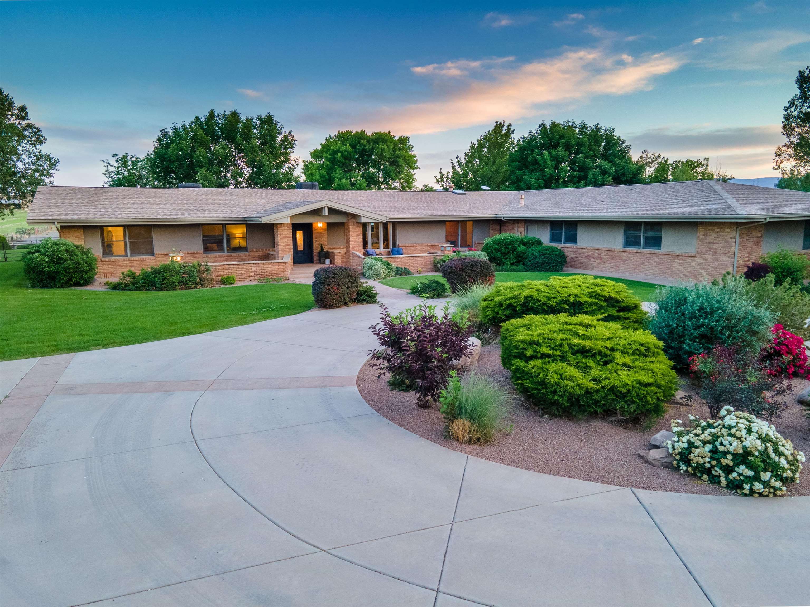 Picturesque custom brick ranch on 7 irrigated acres on East Orchard Mesa. A grand entrance with circular drive greets you as you enter this beautifully landscaped property. Showcasing views of both Mt. Garfield and the Grand Mesa, it’s a slice of heaven in Fruit & Wine Country.  The well-appointed kitchen boasts quartz countertops and Thermador stainless steel appliances and opens to a spacious formal dining area and great room. Vaulted ceilings and a custom stone fireplace make the space cozy and inviting. It’s an entertainer’s dream! The home also features a large butler’s pantry off the kitchen with plenty of cabinetry and shelving. Three spacious bedrooms on the main floor all complete with impressive ensuite bathrooms – one suite can be locked off from the rest of the home and has its own exterior entrance. Perfect for a short term rental or private guest suite. A large rec room, additional bedroom and office space are located in the fully finished basement. Generous outdoor patio features a custom pergola and overlooks a beautiful back lawn, 7 irrigated acres, horse corral, horse barn and metal hay barn. Set up for the equine enthusiast and the property boasts water rights for all 7 acres allowing the buyer to plant peaches/grapes or whatever you choose!