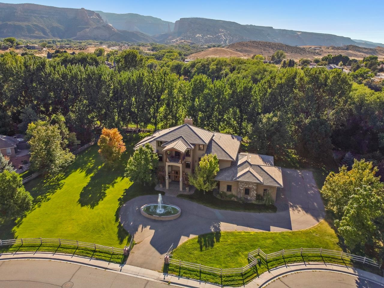Welcome to this incredible custom-built Redlands home in the premier Independence Valley subdivision! You will be awed from the moment you pull up to this 1.1 acre, fully fenced estate with electronic gate, a beautiful fountain in front, a pristine lawn, & mature trees. The three story home has a unique floor plan that optimizes the incredible views of the Bookcliffs & Colorado National Monument. The airy, 3-story entry features custom tile work & multiple closets for storage. The living space beyond has a gas fireplace, built-in nook for a TV & a wet bar complete with mini fridge & microwave off to the side. This space opens up to a covered patio with room to entertain & relax. You’ll find two additional bedrooms, each with a full en suite bath & walk-in closet, as well as a theater room, half bath for guests, & the laundry room on this level. The elevator  is by the entrance from the garage, which makes transporting groceries to the main level a breeze. This second story has another large living room & fireplace & both formal and informal dining rooms. The gorgeous chef's kitchen has a 6-burner gas stove, double wall ovens, two microwaves, a walk-in & walk-through pantry, beautiful granite slab countertops & plenty of storage. You’ll also find a large guest suite with an attached 4-piece, 3/4 bathroom & walk-in closet, a half bath, & an office. The primary suite is also on the second level & is a true retreat, with private deck access, a large sitting area, a 5-piece bath including a luxurious steam shower, a 12x20 dressing room in addition to a walk-in closet, a gas fireplace, & stunning views. The covered deck on this level is perfect for alfresco dining & watching the sunsets. The third story is accessible by both the elevator & stairs, & includes a large bonus room, that while currently used as a craft room has potential to be an excellent executive office or entertainment space, that has another wet bar with a drink fridge & microwave, a half bath, a large closet, & a private open patio with views of the surrounding area & mountains. If this home isn't jaw dropping enough, the oversized 3-bay, 4-car garage with an RV bay & built-in storage might do the trick, giving you plenty of room for storage, tools, toys, hobbies, & vehicles. With additional space behind the garage for parking, you’ll have no shortage of room for adventure vehicles. Close to schools, trails, shopping, & more, this is a fantastic find in Western Colorado - book a showing today!