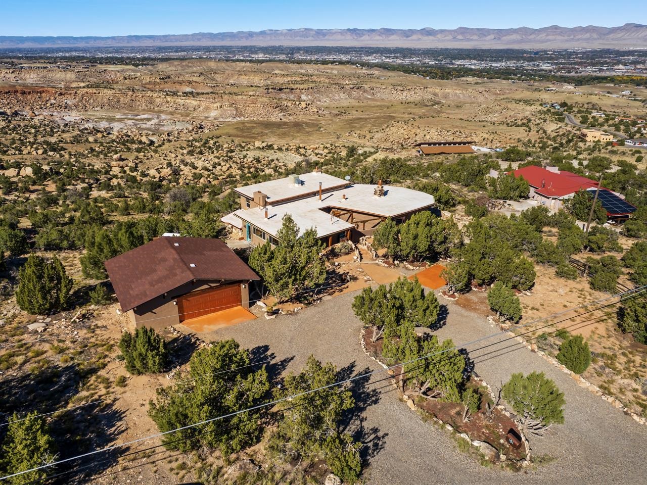 Welcome to this exquisite property featuring some of the most breathtaking views in all of Grand Junction, CO! The sweeping vistas stretch from the majestic red rock cliffs of the Colorado National Monument, across the valley to the rugged Bookcliffs, and extend eastward to the awe-inspiring Grand Mesa. As the sun sets, witness the enchanting city lights of Grand Junction twinkling like stars before your eyes. Nestled adjacent to the Tabeguache/Lunch Loops Trail system, this home offers a direct connection to the renowned Holy Cross Trail, marked by a historic wooden cross erected by the original homeowners. Originally crafted by an artist in the 1960s, this unique home has undergone an extensive renovation, blending modern elegance with artistic charm. Recently updated with new paint featuring contemporary metallic accent walls, fresh carpeting, plumbing and cooling system in good working order, a Kinetico water softener, a new boiler system, and a distribution pump for the private well and cistern—a true luxury in the coveted Little Park Rd neighborhood. Step inside to discover a masterful layout accentuating the architectural brilliance, showcasing four fireplaces and three spacious living areas. The resplendent hardwood floors pave the way to a versatile office, affectionately dubbed "the rock room," serving as an ideal space for yoga, workouts, or moments of meditation. The kitchen, thoughtfully designed with modern stainless steel appliances and large windows, allows you to immerse yourself in the stunning views while cooking and entertaining. Embrace the outdoors with a captivating fire pit and bench just beyond the back door, creating the perfect setting to relish panoramic vistas and create cherished memories. Adjacent to the detached garage, a convenient storage building awaits, ready to house your toys and tools, while an additional deck provides a serene spot to unwind and soak in the beauty that surrounds you. Indulge in a world of beauty and sophistication as you make this truly one-of-a-kind home your own. Don't miss this extraordinary opportunity to experience the epitome of Grand Valley living. Schedule your exclusive showing today!