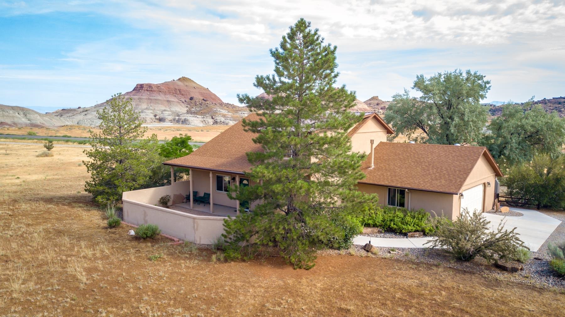 This lovely home is surrounded by 2 acres and sits below the Colorado National Monument,  with 360 degree views!  A very desirable location  This home is loved and well maintained, with amazing views from every window!  Walk through the private front courtyard to enter this stunning home!  The living  room includes a gorgeous floor to ceiling stone surround gas fireplace, with a blower for those cozy winter nights!  From the living room, the open concept leads you into the dining room and the kitchen.  There is a spacious family room off of the kitchen with french doors to the back patio.  A privacy fence encloses the amazing backyard.  The Primary Bedroom is on the main level with the upper level boasting an office, 2 more bedrooms and a full bath. The loft overlooks the living room and fireplace.  Outside is a 32 x 28 Workshop with covered RV parking and additional covered parking for vehicles and toys.  The workshop includes a platform lift for working on your projects.   Plenty of room for all your hobbies! BRAND NEW ROOF!! on home and the  Workshop!. Located close to the east Monument entrance, Lunch LoopsTrailhead, and downtown!    Incredible opportunity to own an amazing property!  Schedule your showing today!