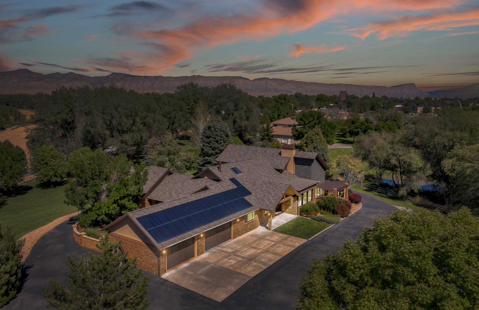 2625 H Road is a Grand Junction Estate where history and charm come together to create an amazing home. Formally known as the Suplizio House, this gorgeous property sprawls across 4.5 acres and boasts over 6000 square feet of living space between the main home and ADU, a 2 car attached garage and 2000 square foot detached temperature controlled shop with exercise room. A dedicated irrigation pond, custom play-set, lush landscaping, trees and garden areas, plus multiple lovely patios create an outdoor oasis. This immaculate home has been well maintained and updated over the years. There are 4 bedrooms, each with an attached ensuite. The primary bedroom features an impressive closet, a private fireplace and a deck with views of Mount Garfield and the Mesa. A dedicated office and guest bathroom are situated perfectly behind the bar area and game room. A dual fireplace to the game room and living room creates warmth and unity between the spaces. A chefs kitchen with a 48” Thermador Gas Range and Subzero Refrigerator are only a couple of the kitchen’s highlights. And the downstairs theatre room with a private bathroom is an amazing place to unwind. With transitional and timeless finishes throughout, this home will stand the test of time. From the travertine tile that was imported from Turkey to the story of the bar top from a bar near Wrigley Field in Chicago, this home is beautiful and full of stories. The home, shop and adu has recently had a new roof and gutters installed, along with owned solar to help with energy efficiency on both the home and shop. A little character was added with decorative shake siding to compliment the original brick and newer stucco work. The home feels bright and airy with cathedral ceilings that welcome you, along with fresh paint and stained beams that highlight the homes architectural lines. New decorative lighting throughout the home updates the overall aesthetic of each living space. The new mudroom, off of the attached 2 car garage, provides additional storage and place for all the things you want drop at the door.  A mini split was added to the ADU to provide a comfortable space for guests or a home office. Attached to the ADU is a perfect little greenhouse with access to garden areas. The 31 acres behind this estate is zoned as a City Park, and is currently farmland. This home offers you comfortable living in a serene setting and is truly a piece of Grand Junction History.