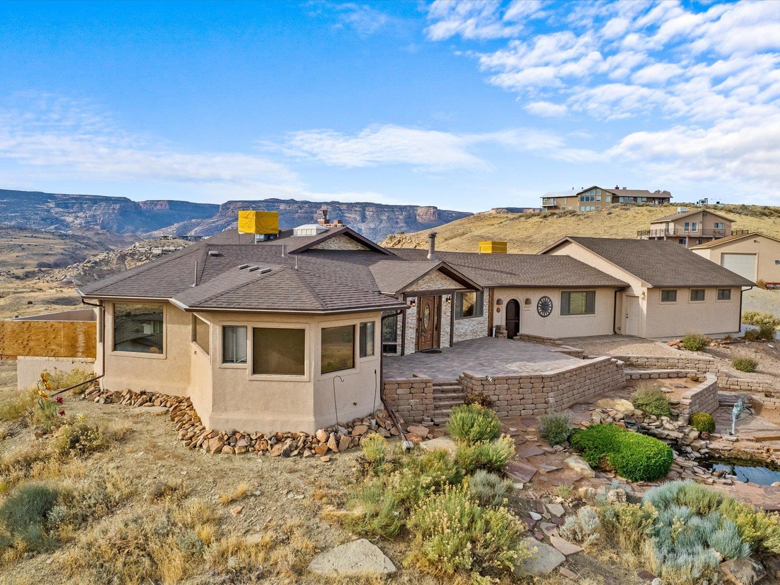 Welcome to your new dream home, with views  of the beautiful Western Slpoe like no other.  This stunning home is screaming with character, begining with with circle driveway, an inviting staircase & waterfall fountain, stacked stone enterway.  Inside, an  immediate open atmosphere with Saltillo tile, & Vaulted tongue and groove ceilings the living & dining rooms anchored with floor to ceiling fireplace, while you look outside to the  Mpnumrnt, VIEWS from every window, The Monument road, Saun Juans , Pinon Mesa, Grand Mesa, Mt. Garfield, the Bookcliffs, WOW., all this has French doors to the decks.This flows into the kitchen with more outstanding views and Lots of cabinets, a pantry., & powder room and extra storage.  Continuing through this cozy home, the master bedroom  French doors opening to  the deck,& VIEWS  more  of the southwestern style,  bathroom, walk in closet, double sinks, free standing jacuzzi tub, walk in shower, and laundry room.  down the hall is  an extremely spacious family room, medis, office,  or whatever your imagination can think of,  AND  a 3 car garage.                        Downstairs  welcomes you into another gorgeous living room with a kitchenette included.   Two bedrooms have slide doors leading you out to another tiled entertainment space with more Colorado views.  A full bathroom, extra storage and closet space, and two utility closets.   If you aren't excited enough about this one-of-a-kind home, it has lots of parking space, and two more sheds for more storage.  All maintenance is up to date ,Landscape is beautiful and Native (no lawn)  This is a home you will not want to miss!  Continuos Hot WATER thru heating system
