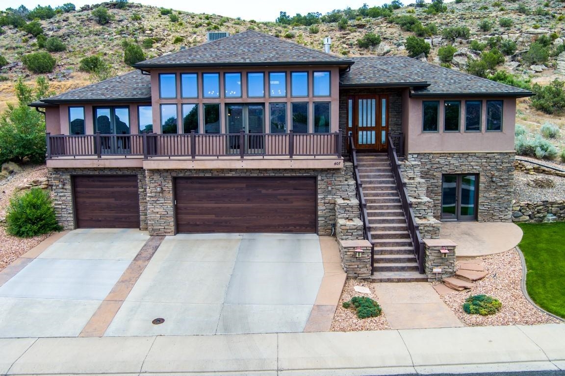 Amazing views of the Colorado National Monument in this stunning 2 story home! The living room features two rows of windows wall to wall, and French doors that open onto the front deck. The gas fireplace gives a warm feel to the room, and the cabinets beneath are cooled to protect the AV equipment and wiring. The living room is open into the dining and kitchen areas, and from the dining room are more French doors to go out onto the back patio and the open space behind the home. The primary bedroom, on the main floor has a private deck and a large walk in closet. The primary bath has 2 windows looking out into the back patio area and up into the hills beyond. Downstairs is a large open room - can be an office, workout room, music room, game room. There is a HUGE storage room downstairs, and another set of French doors to go out front. The oversized 3 car garage also has a separate storage closet/room. Backing up to open space, there are hiking and biking trails literally right outside your back door.
