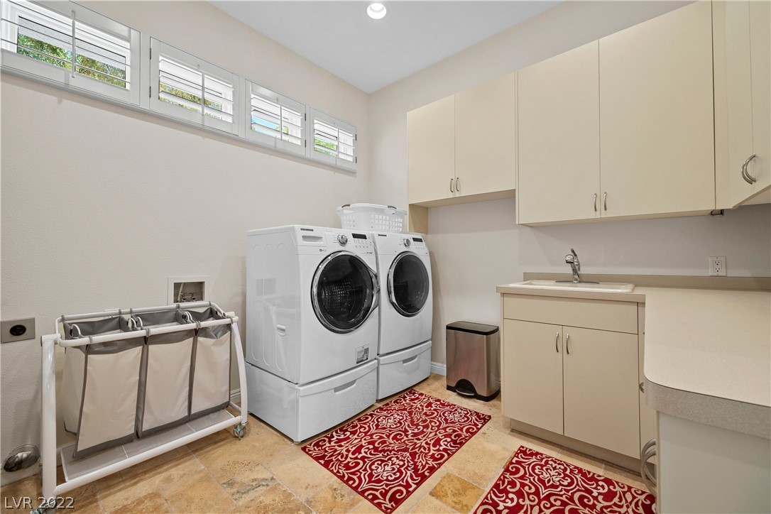 Large laundry room with utility sink and extensive cabinetry.