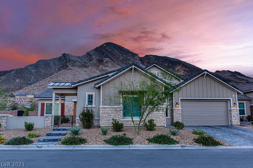Twilight view of home with stunning curb appeal and beautiful elevation set against mountain background!  Note the pavered drive and walkway, along with iron entry gate set on an oversized corner lot.