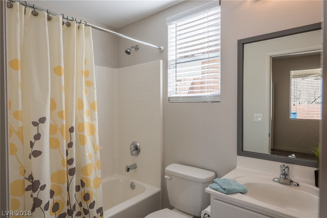 Full bathroom located at downstairs master offers a tub/shower combo, and single basin sink with a storage cabinet.  Custom framed mirror and natural light from the window.