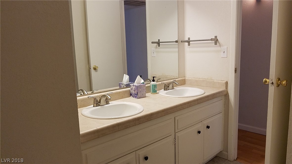Hall bathroom with double sinks; tile counter and flooring.  Room measures 7x9.