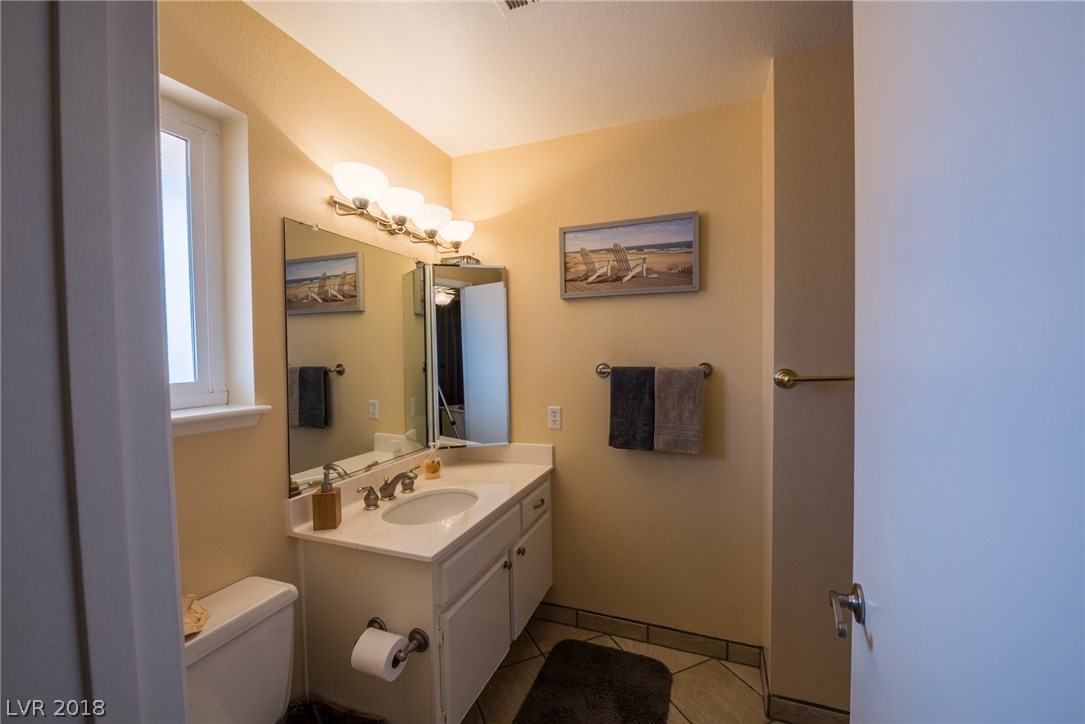 This master bathroom has been updated with newer countertops, tile floors, new paint & toilet.  You will also find a window here that allows for fresh air & natural light.