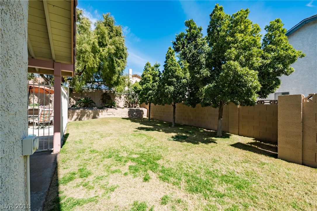 Large side yard with tons of grass, trees, shrubs & play area.  Plus enjoy the covered patio & relax safely as the pool is separated by a built-in safety gate.
