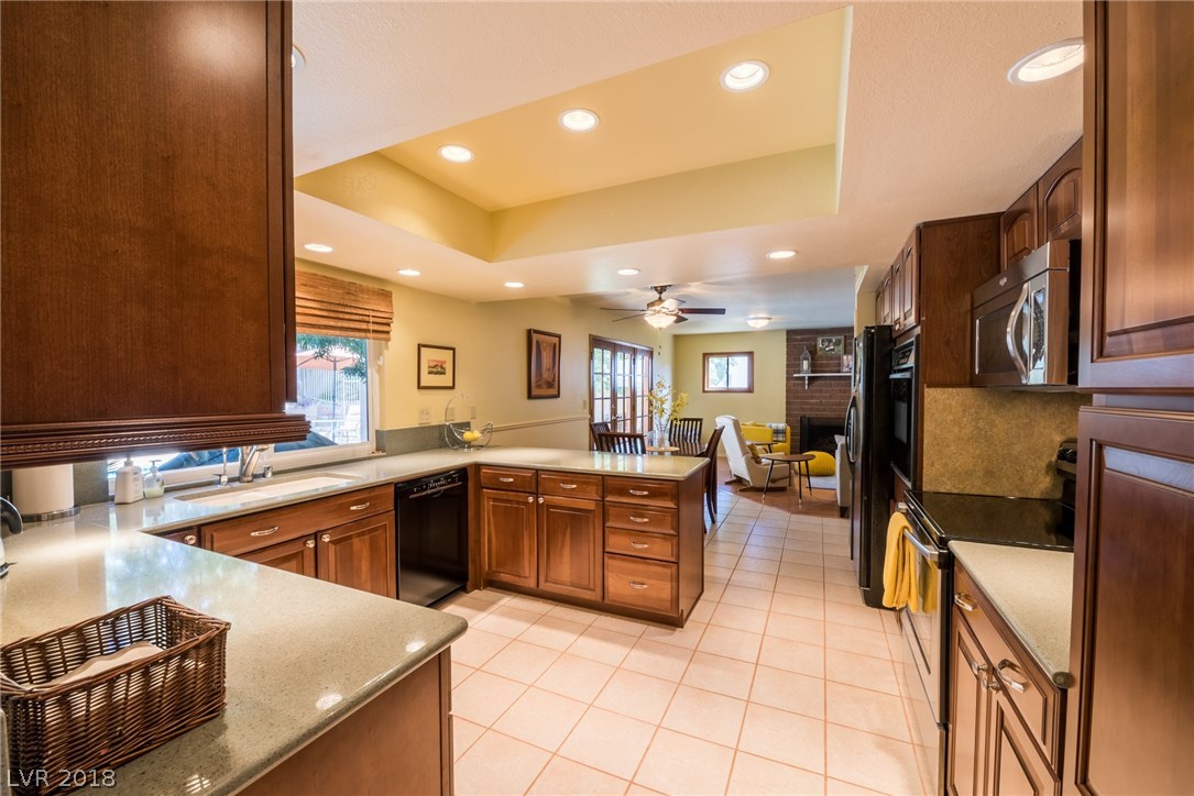 Gorgeously remodeled kitchen offers cherry cabinets with glass panes, quartz countertops, upgraded appliances, 2nd built-in oven, backsplash, tile floors, breakfast bar, and window overlooking your delightful backyard.