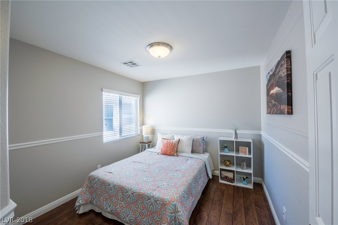 Second bedroom with dark wood floos, two-tone neutral paint & large window to allow natural light.