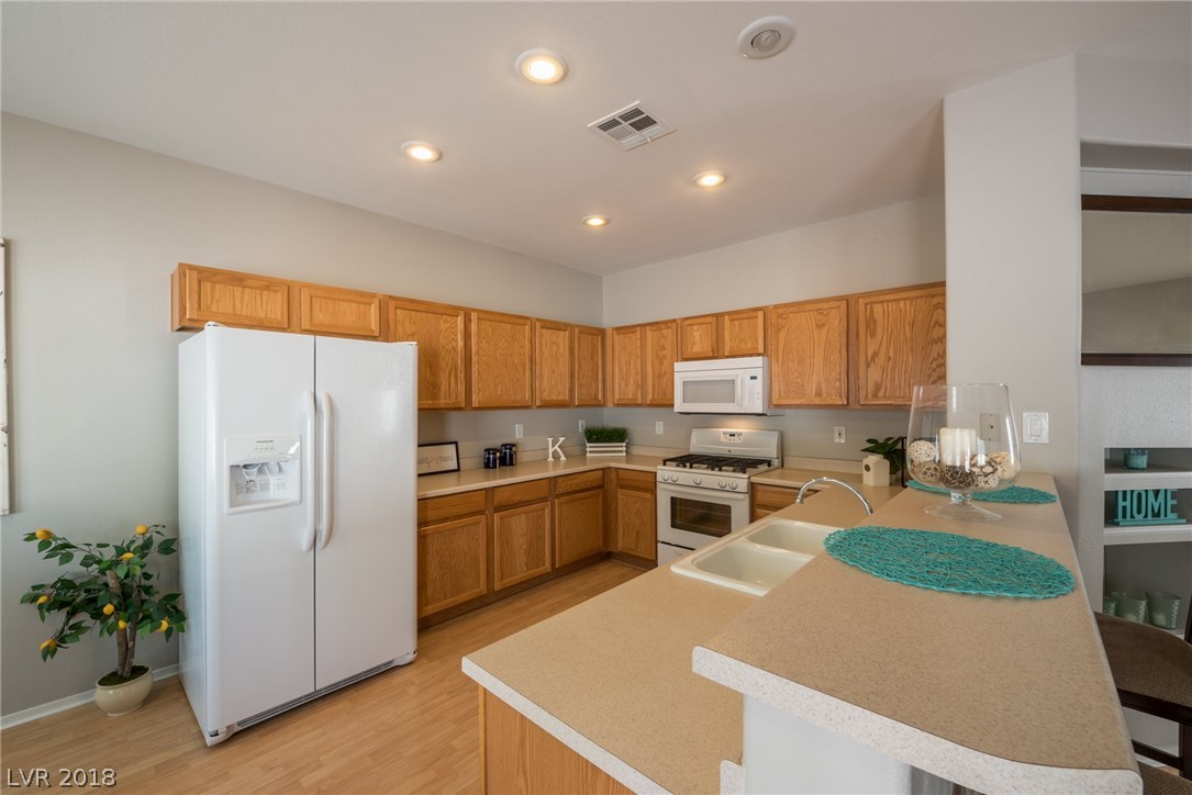 All appliances are included in this bright & airy beautiful kitchen.  Lots of cabinet space, recessed lighting, laminate wood floors, and breakfast bar.