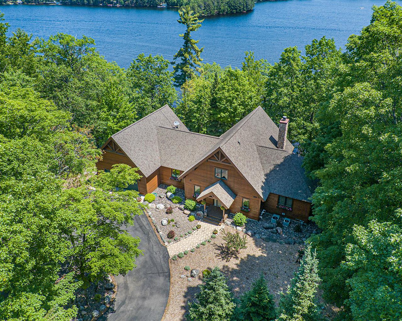 THREE LAKES CHAIN DREAM-Lovely custom cedar home w/225’ of private sand frontage & INCREDIBLE lake views! This spacious home is centrally located on the highly sought after 3-Lks/Eagle River Chain of 28 Lakes & between Three Lakes & Eagle River. Features; soaring wood ceilings, hickory flooring, a beautiful floor to ceiling FP, lakeside wall of windows. Open kitchen/dining area w/hickory cabinetry, SS appliances & peninsula snack bar, main floor primary BR suite w/lakeside deck & Jacuzzi tub. Plenty of room for friends & family in the loft BR suite & finished walkout LL w/large family room that leads to a fabulous stone patio & firepit area. Guests will gather in the convenient screen porch that leads to extensive lakeside decking. Easy access off newly paved roads & close to a boat landing, there’s a circular blacktop drive, an attached insulated garage, dry boathouse at water’s edge & maintenance-free pier. This property delivers the Northwood’s lifestyle you’ve been dreaming of! Buyer to Verify All Measurements