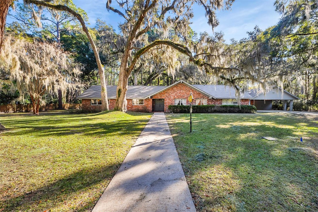 Imagine living on a beautiful island with NO TRAFFIC LIGHTS! This "Jekyll Island Jewel" is pretty, comfortable, and pristine! 4 bedrooms, 3 full baths, lots of space to spread out, entertain, and relax. Home sits on TWO lots which back up to a beautiful wooded area and has plenty of natural light. You will love the rich wood flooring in the back living areas, the spacious kitchen with a double oven, double stainless sinks, a dining area with a bay window, a "spice closet" and storage, and FOUR walk-in closets. The cozy den off the kitchen has a wood-burning fireplace and a skylight. Formal living and dining rooms plus a bonus room behind the garage. We like the full "beach bath" off the garage entrance = perfect for rinsing off from a day at the beach or playing golf. The huge 3-car carport PLUS single-car garage provides plenty of parking and storage. There is even more storage in the attic with TWO access ladders. Jekyll's beautiful beaches, golf courses, and Historic District are a short drive, golf cart ride or bike ride away! A great opportunity on Jekyll Island!