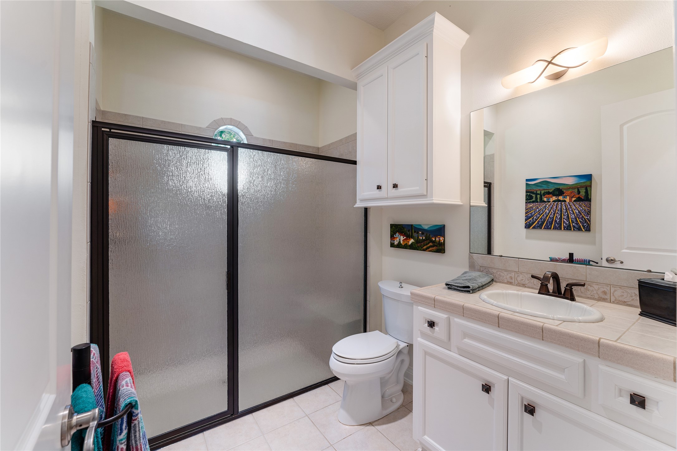 The guest bathroom is equipped with a single vanity and a walk-in shower with a glass enclosure.
