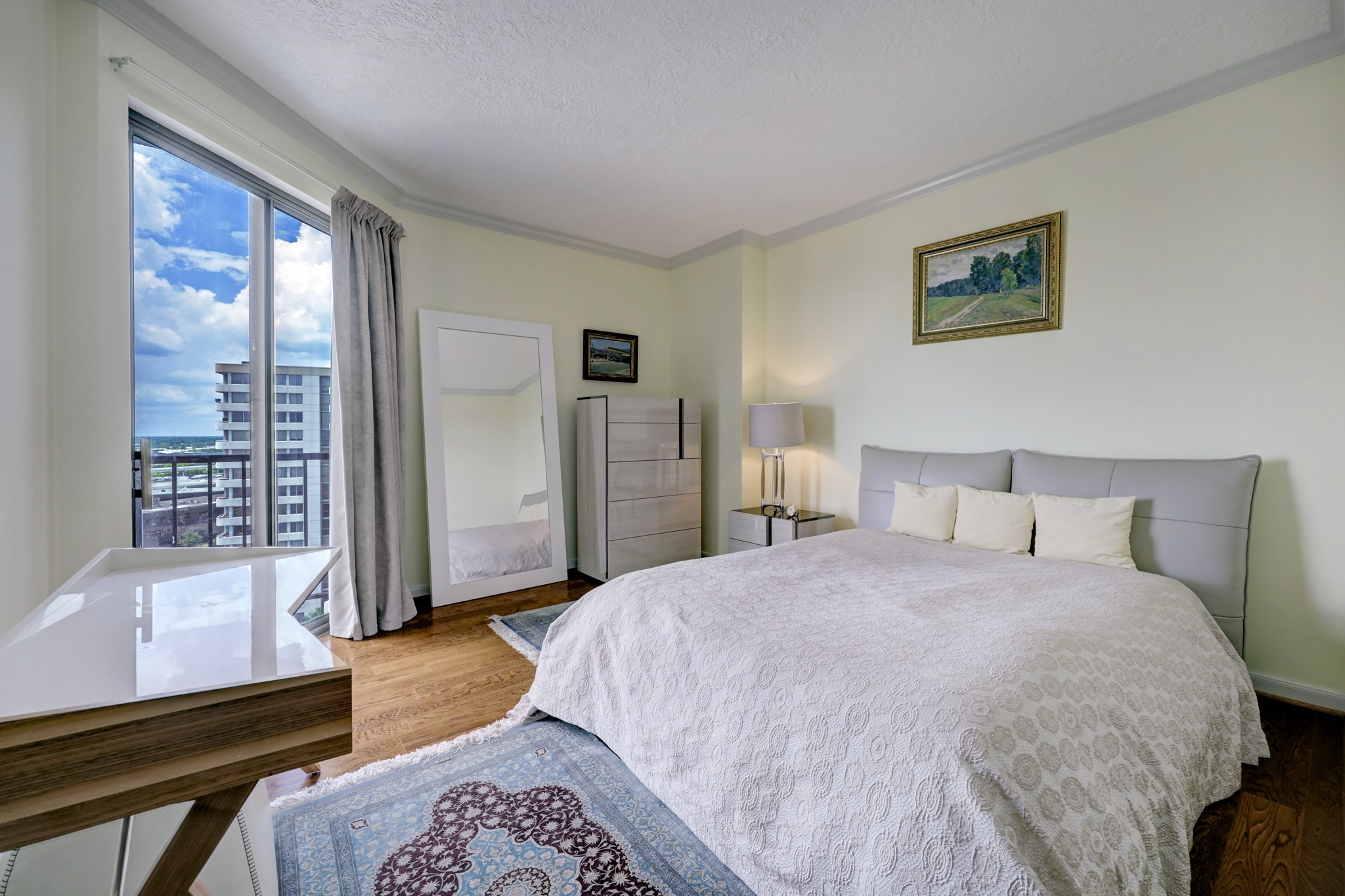The primary bedroom has two walk-in closets and hardwood flooring. Sliding door access to the balcony