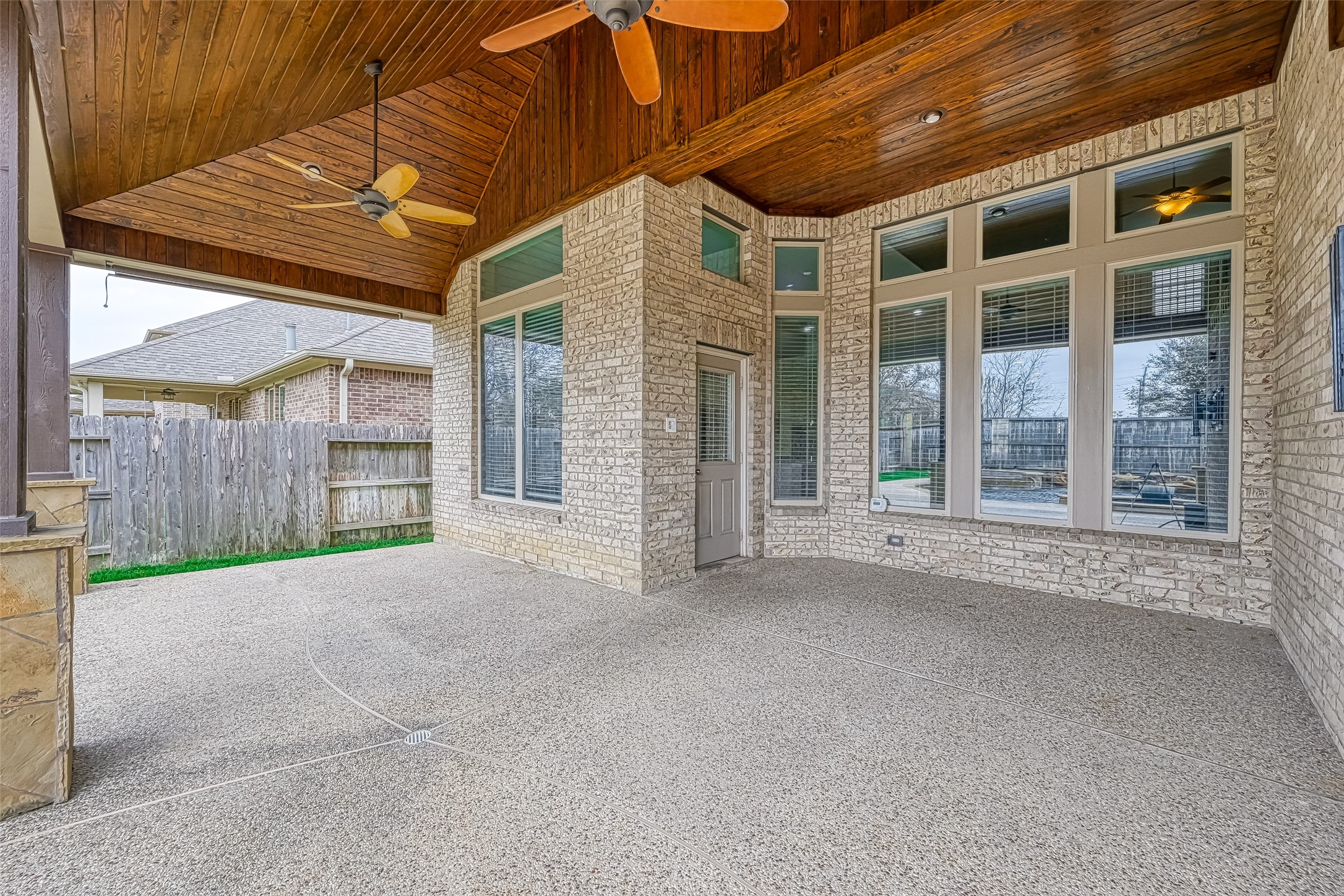 Awesome covered back patio with wood  ceiling and fans to stay cool on those hot summer days.