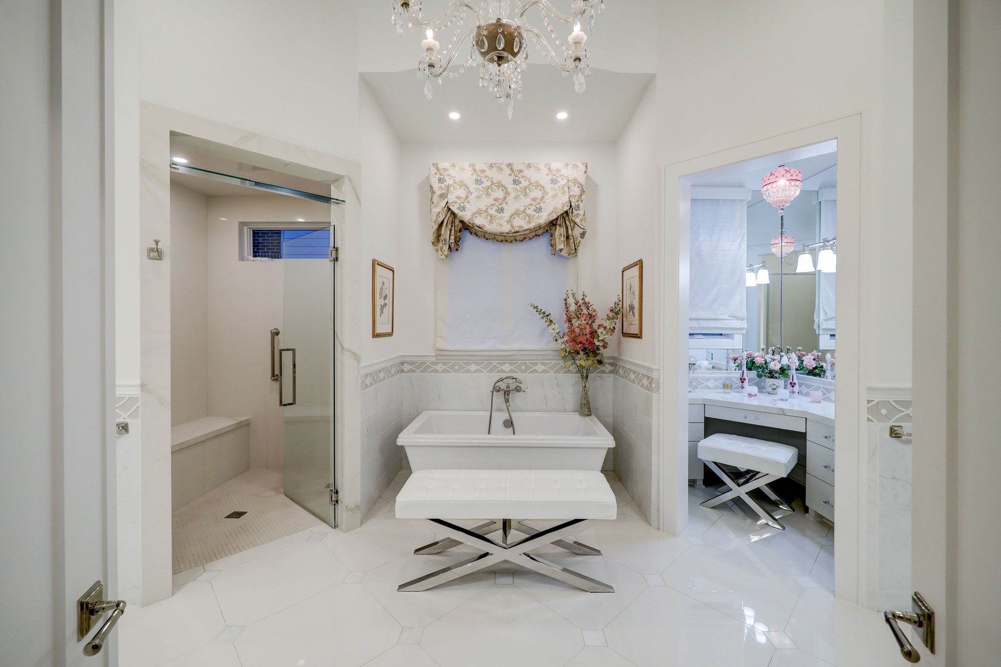 [Primary Bath]
The primary bath features dual sides with two water closets, one fitted with a bidet; porcelain-deck sink cabinets; marble and glass backsplashes; marble tile floors; zero-entry steam shower; soaking tub; and a separate vanity room with vanity cabinet, mirrored wall, and specialty lighting.