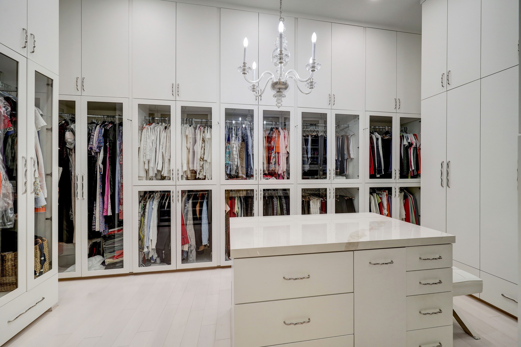 [Primary Closet 1
Bespoke closets offer vestibule entries, packing shelves, glass-front wardrobe and cabinet storage, and custom-fitted accessories storage. One closet includes a beverage bar and under-counter refrigerator.