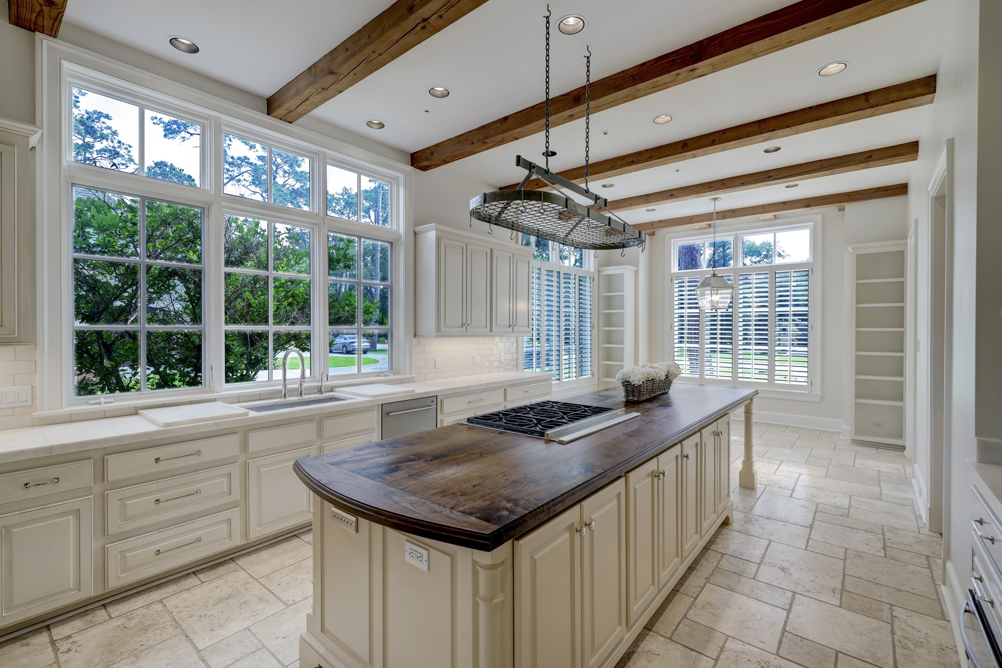 Light filled Kitchen with beautiful finishes including marble countertops, wood island, subway tile backsplash, and limestone floors.