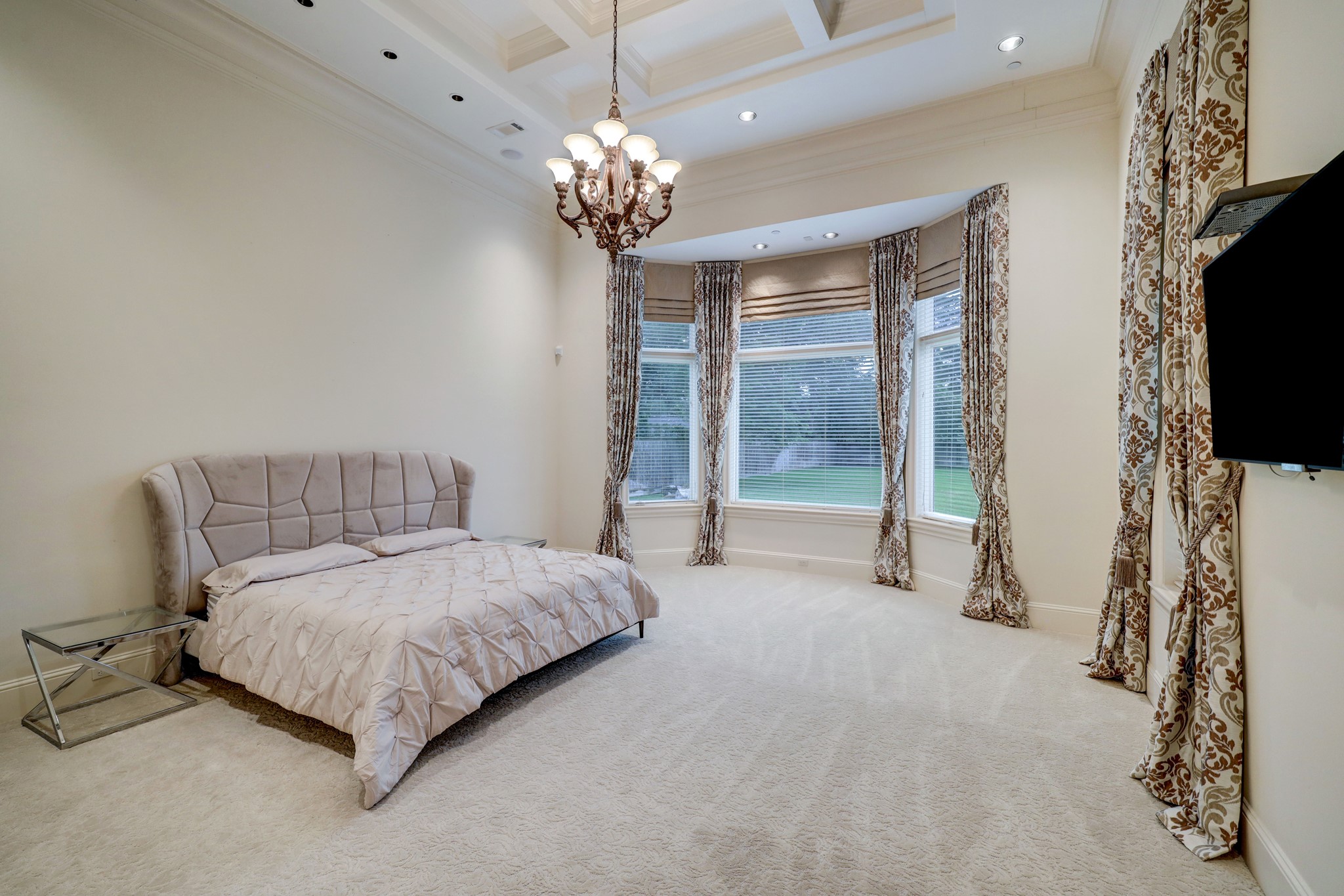 The Primary Bedroom is located on the first floor and features coffered ceilings, carpet, bay windows and a spa-like en-suite bathroom.