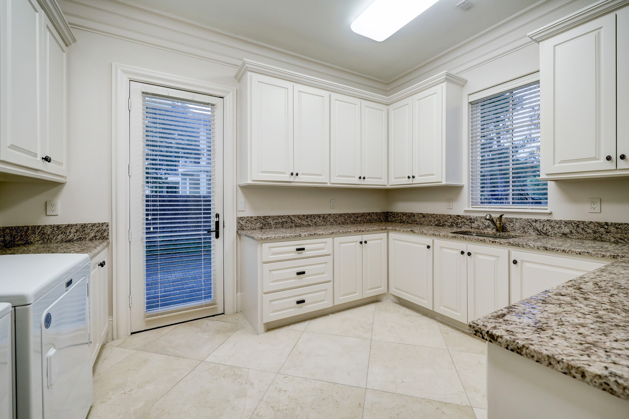 The Utility Room features room for side by side washer/dryer units, utility sink, granite counters and plenty of folding and storage space. Door leads to outside.