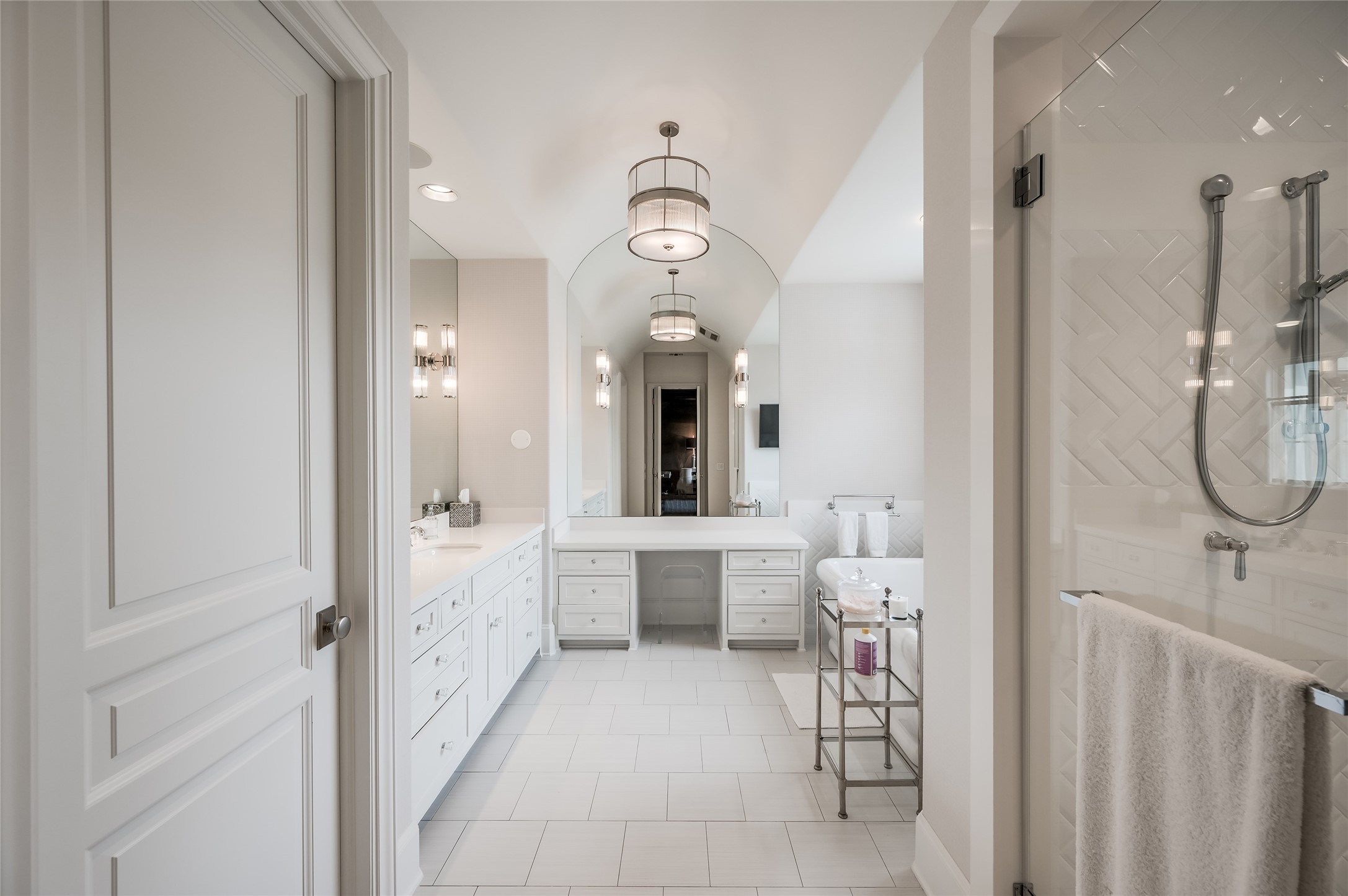 [Primary Bath]
The dual primary bath offers privacy, two water closets, a double-entry seamless-glass shower, soaking tub, marble sink decks and floor, and two bespoke walk-in closets. Note barrel ceiling.