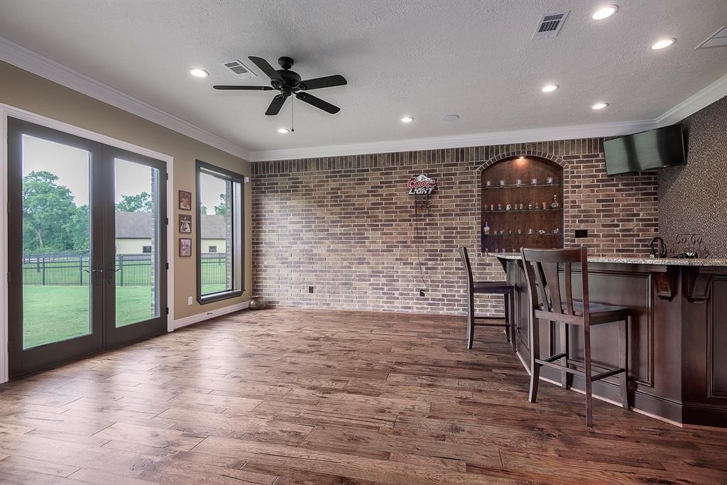 Downstairs game room with rich wood floors and French doors, conveniently located off the kitchen area.