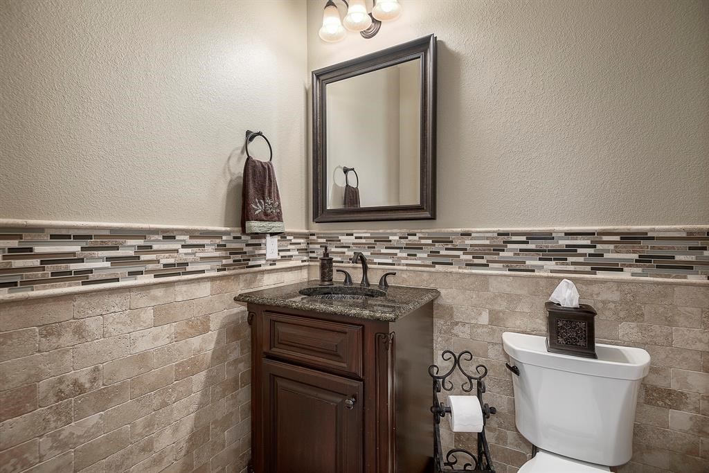 Powder room on the first floor with travertine tile and wainscoting.