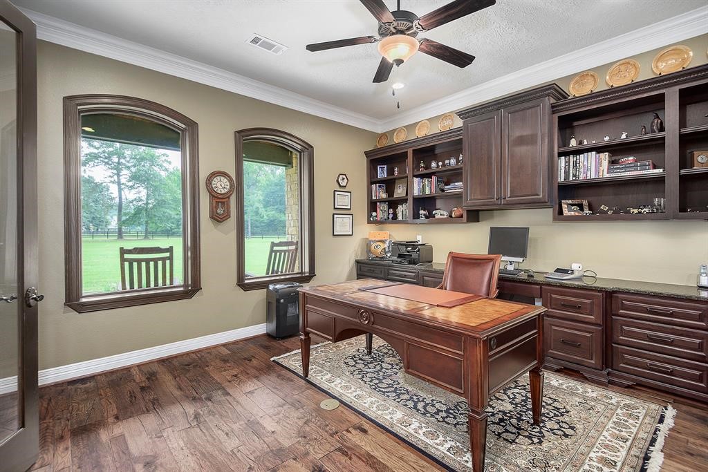 Large study with French doors located off the foyer with wood floors and custom stained built-in cabinets.