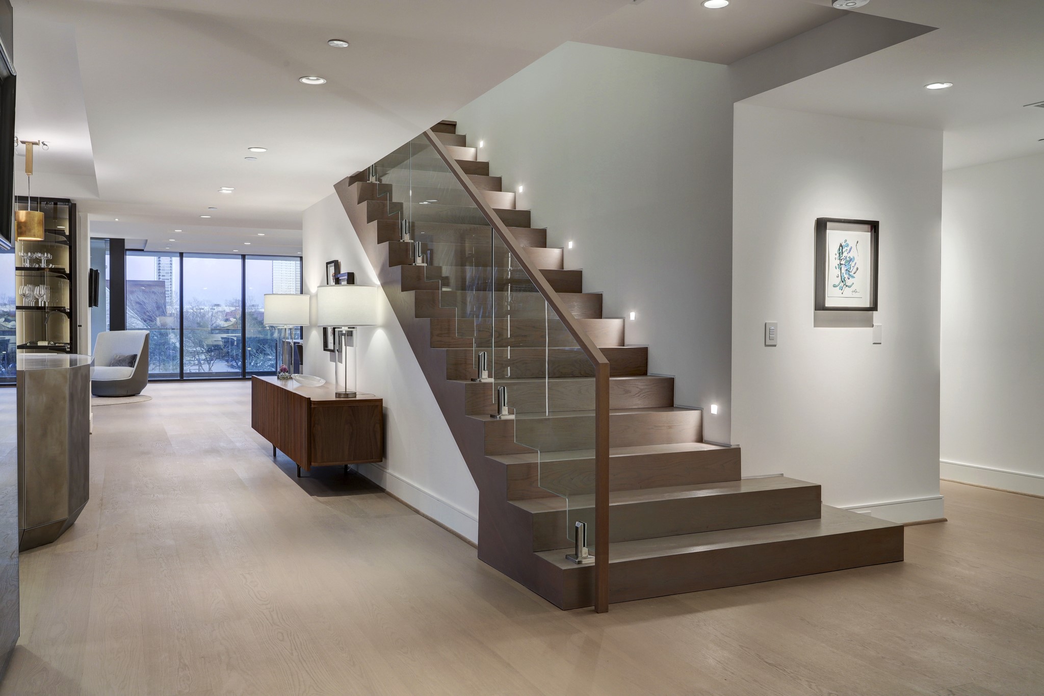 On the main floor of the 7,582-square-foot home, you're invited into sprawling open-plan living and dining areas lined with floor-to-ceiling windows and unimpeded open-sky views. The staircase shown here is a true work of art.