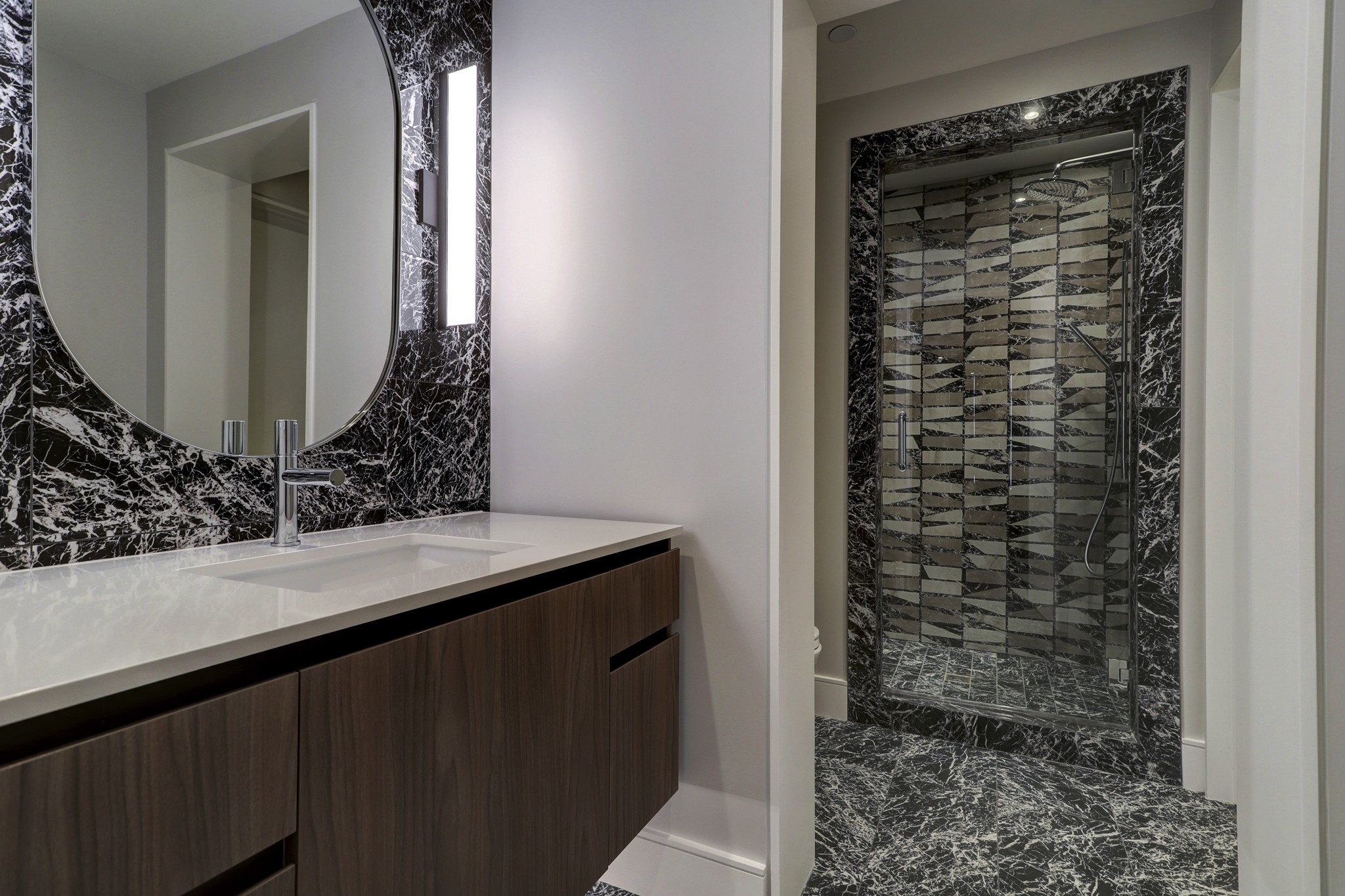The media room's attached bath continues the lounge's moody theme with dark Piemme tile.