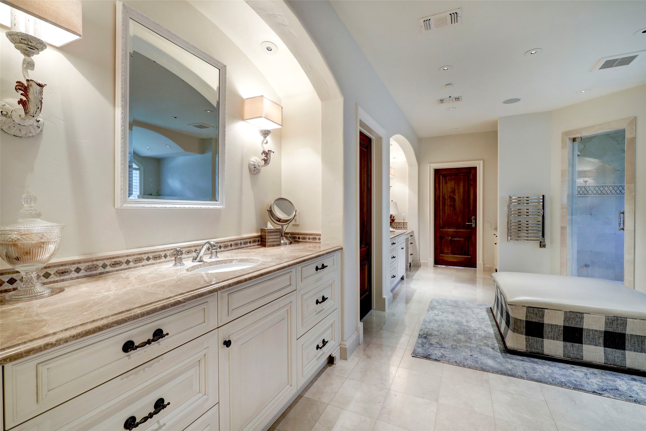 The marble primary bath includes two sinks, vanity area, shower, jetted tub and towel warmer.