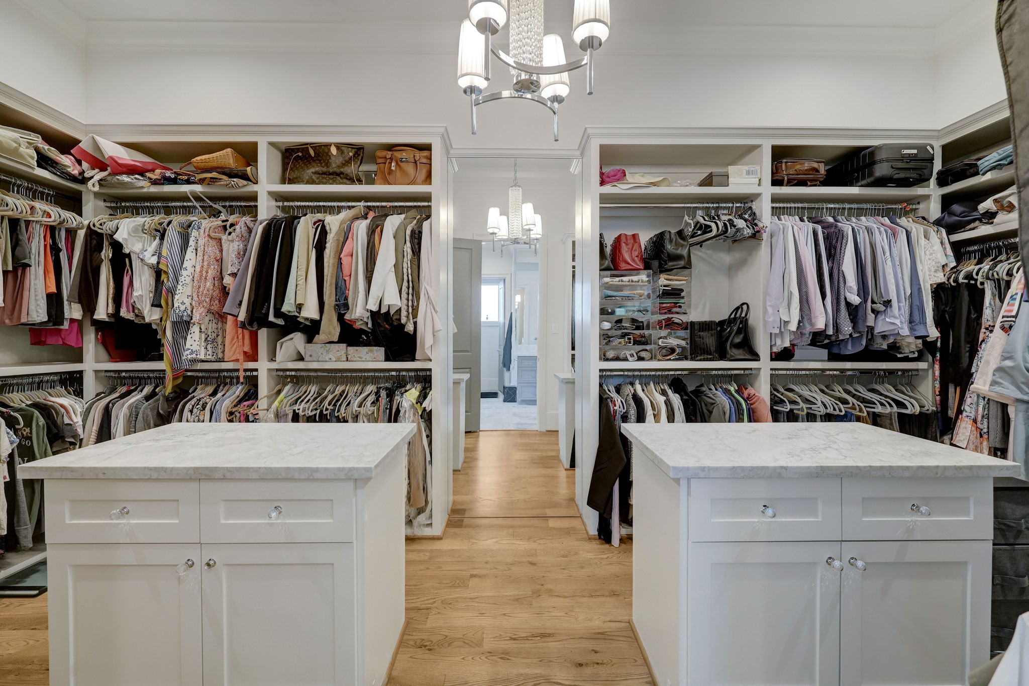 The primary closet features dual islands with built-in storage, several clothing rods, and built-in shelving.