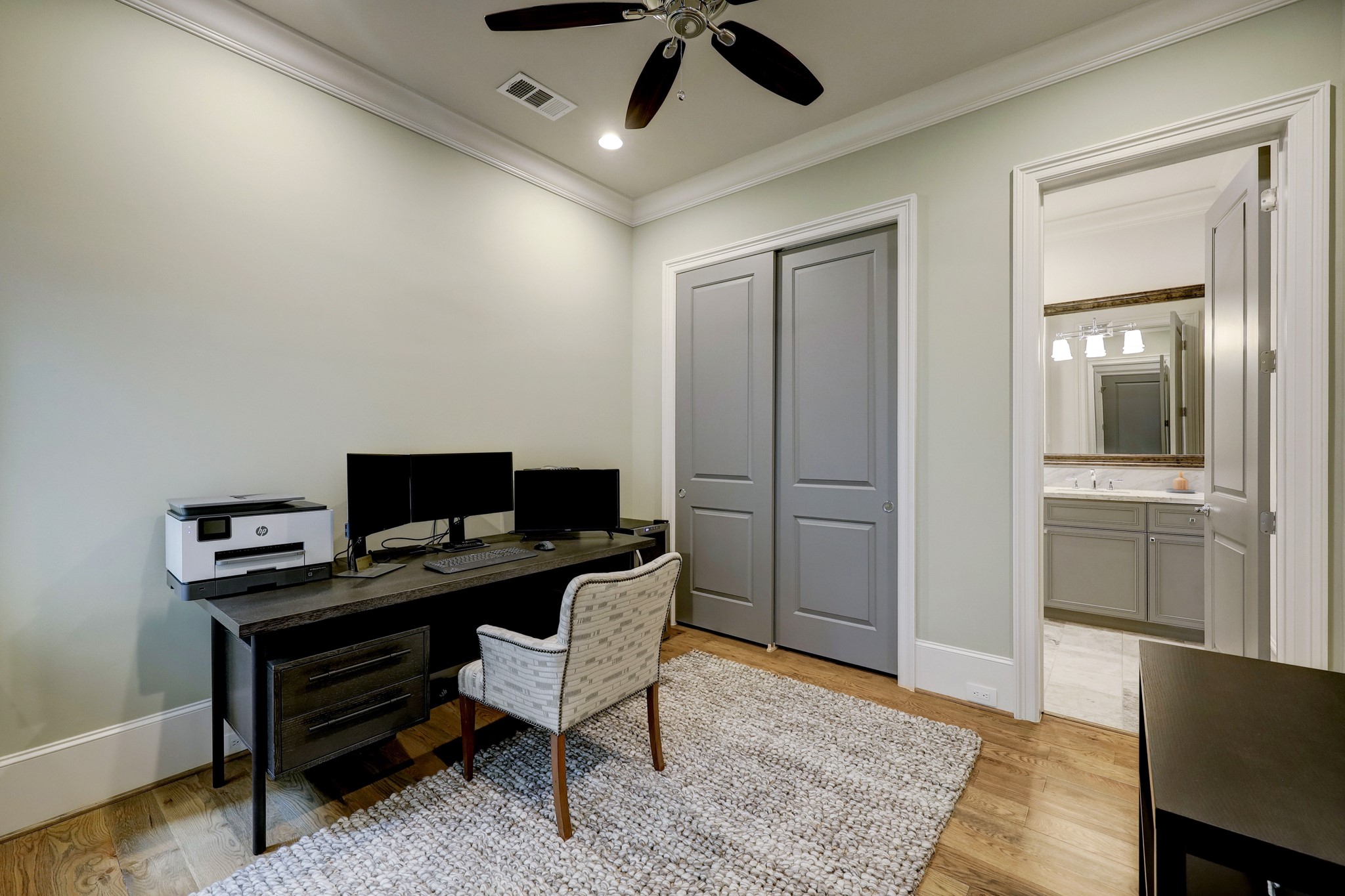 The downstairs secondary bedroom is perfect for a home office or guest room. It features wood flooring, an en-suite bathroom, and access to the backyard.