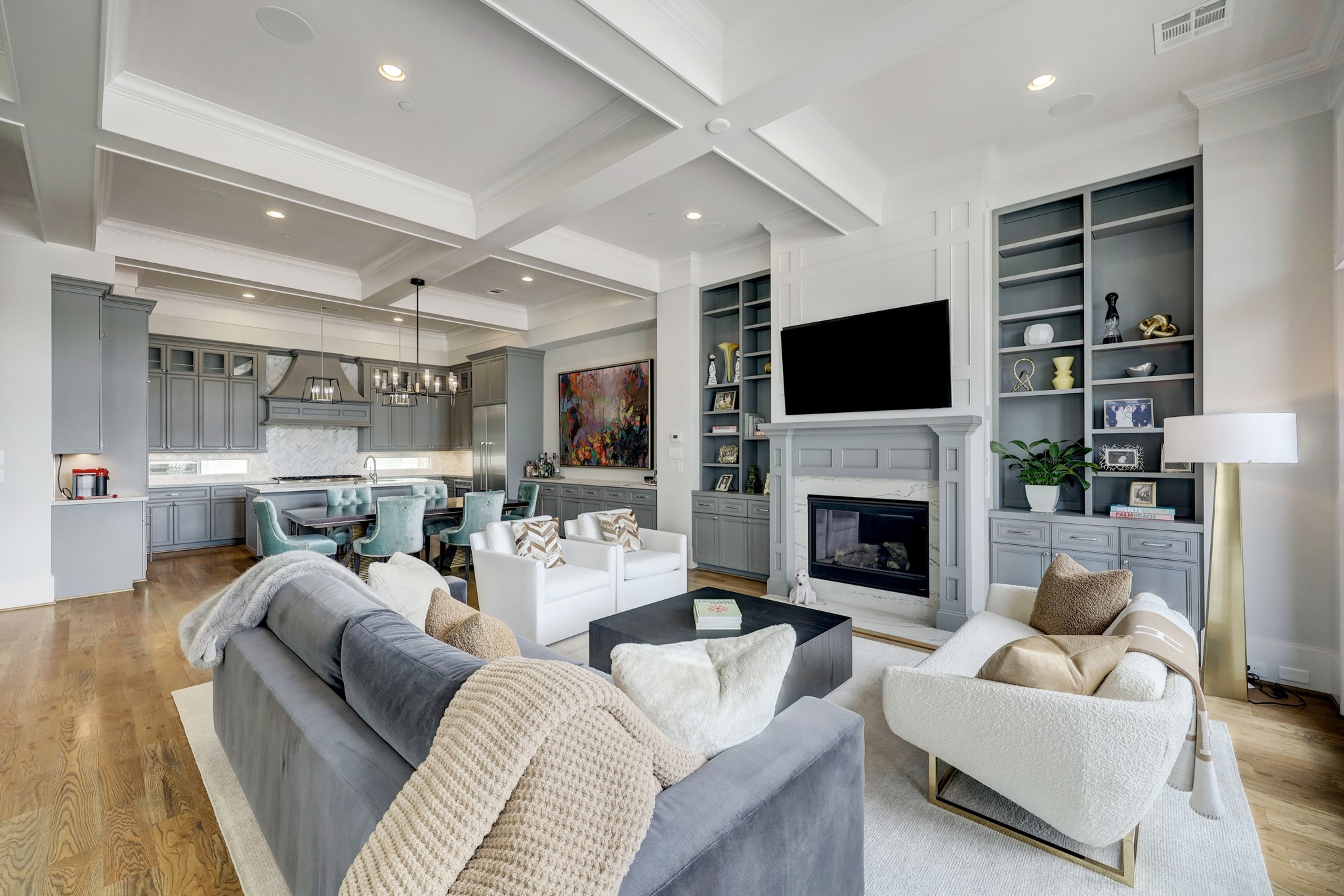 This beautiful open concept living room features a fireplace, coffered ceiling, and built-in shelving and cabinets.