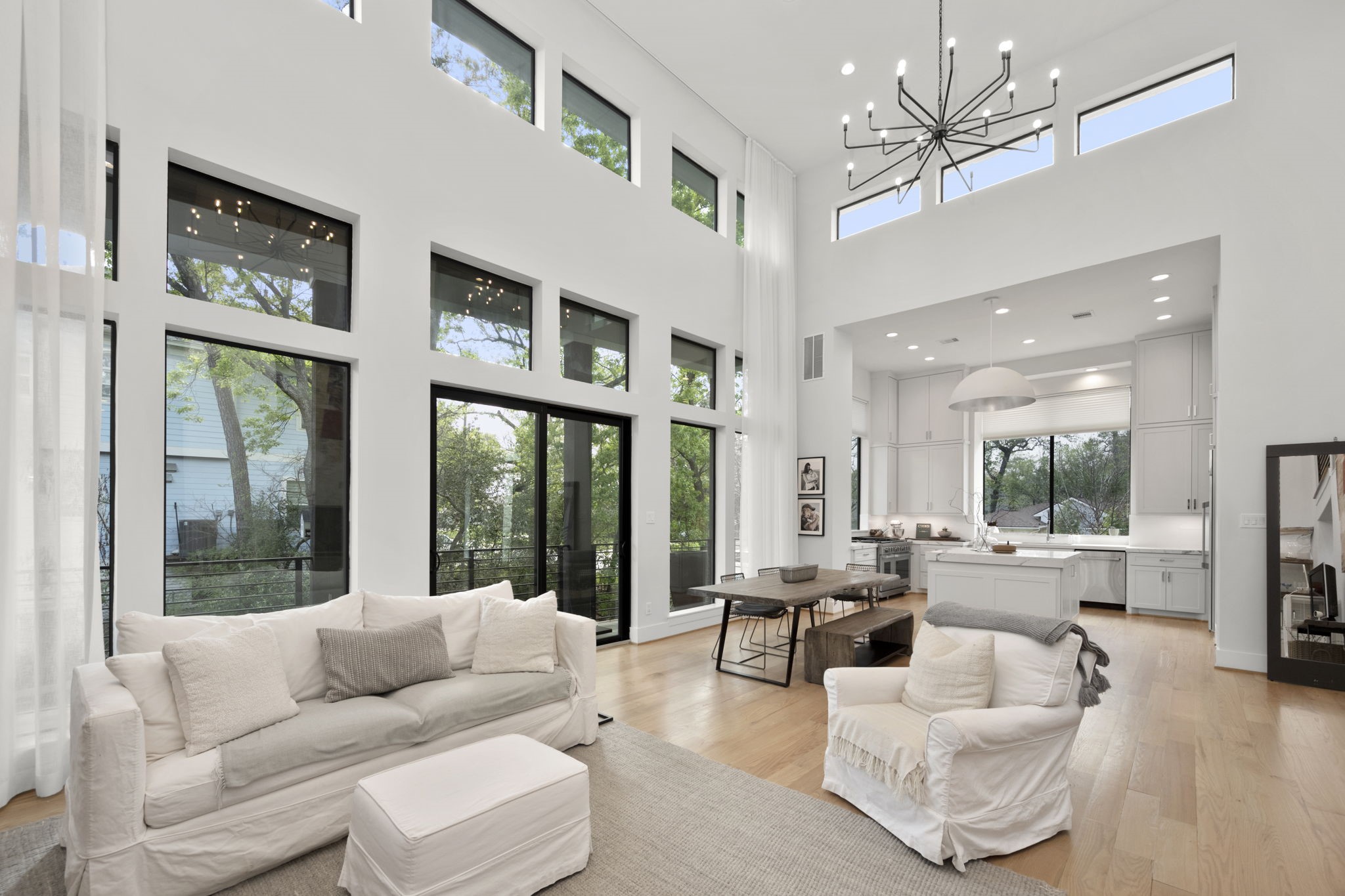 This open concept living is a dream set up for entertaining or everyday living. Light from the large windows, highlighted by custom window panels, bring in warmth and showcase the natural surroundings outdoors.