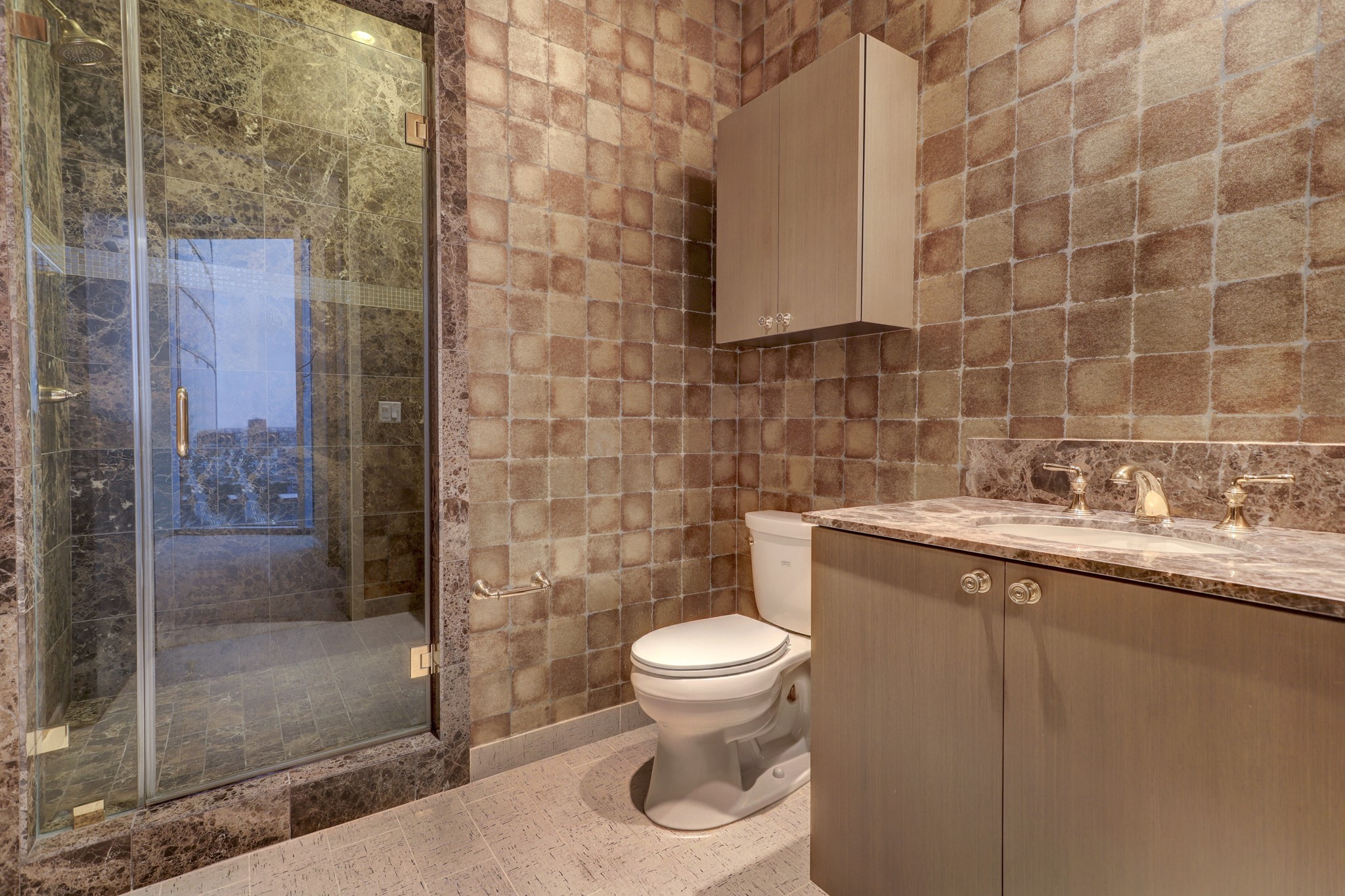 The Secondary Bedroom En-suite Bathroom features decorative wallpaper, walk-in shower with marble surround and sink vanity with a marble countertop.