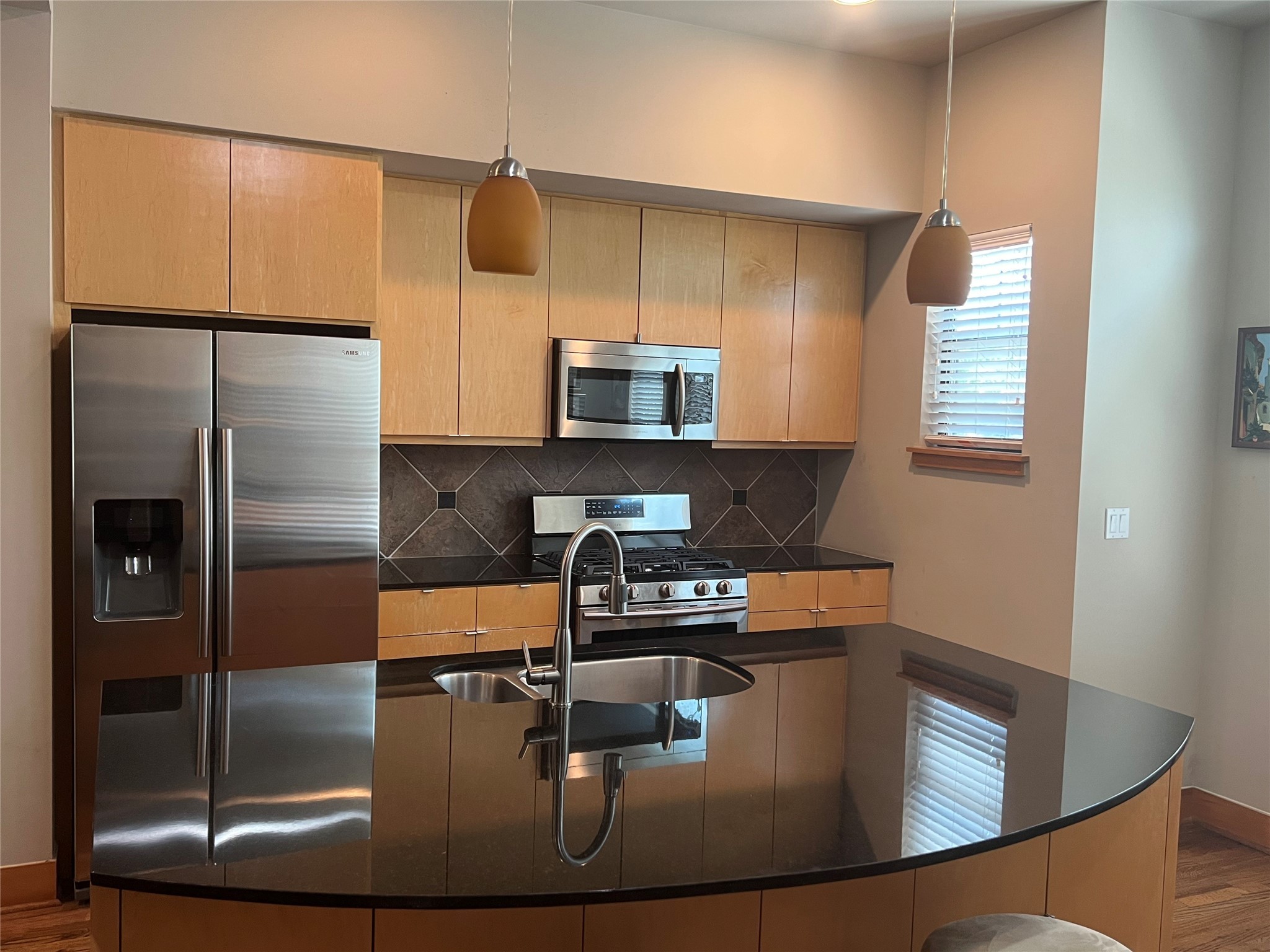 Stunning gourmet kitchen with Samsung stainless appliances, granite counters, recessed lighting with breakfast area.
