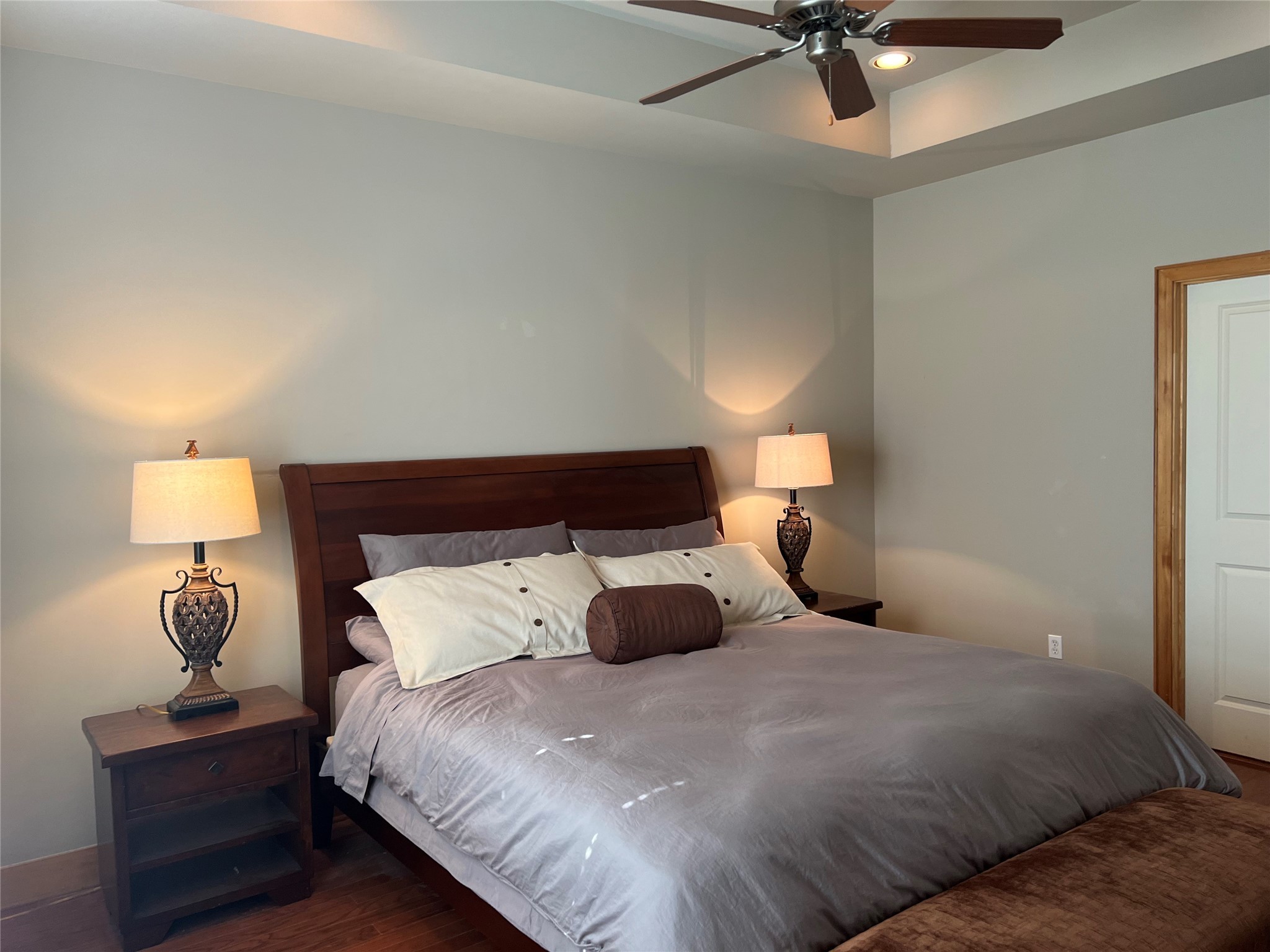 Primary oversized bedroom suite with coffered ceiling, recessed lighting with dimmer, sitting area and hardwood floors.