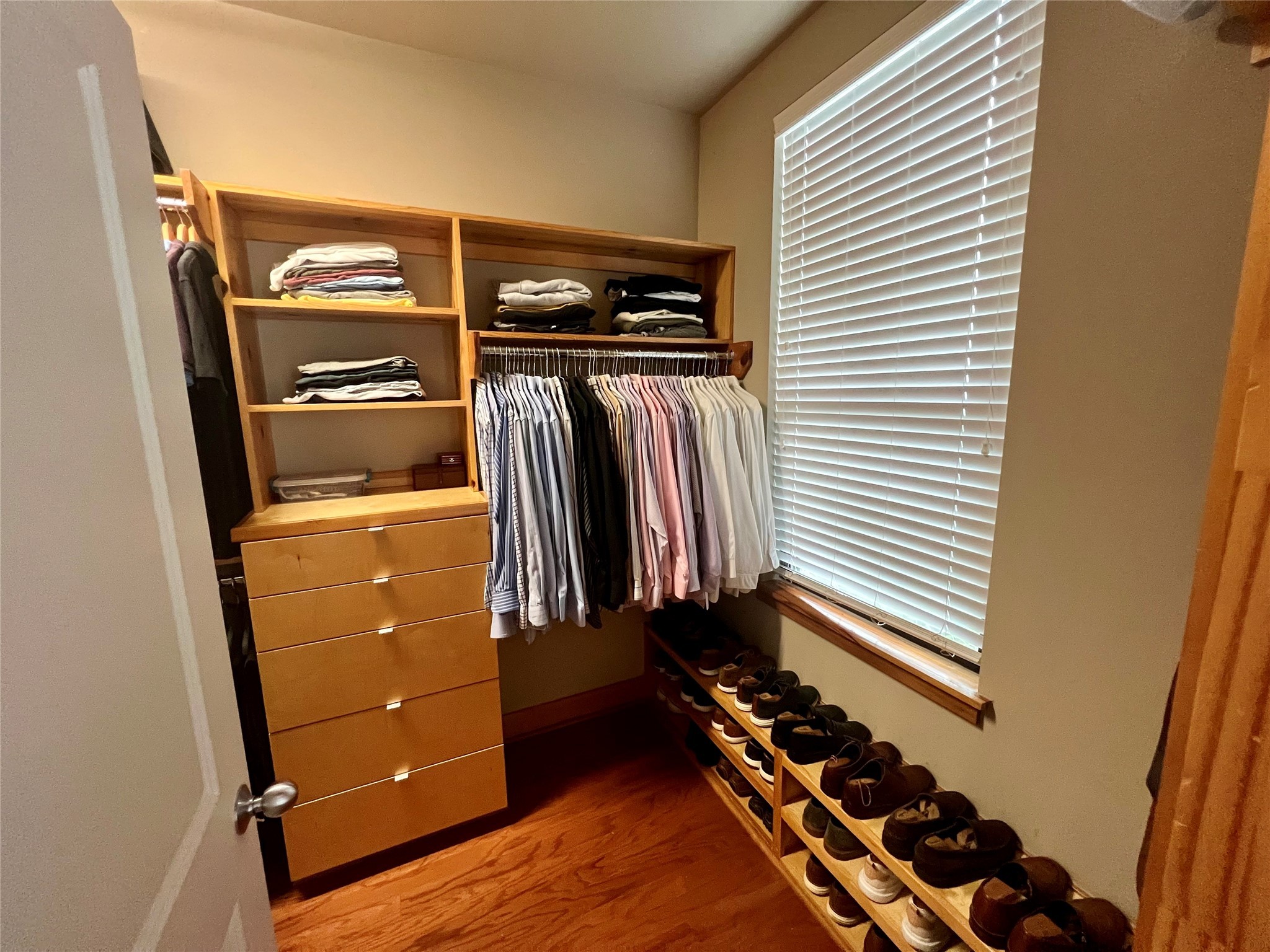 Walk-in closet with custom built-ins and hardwood floors.