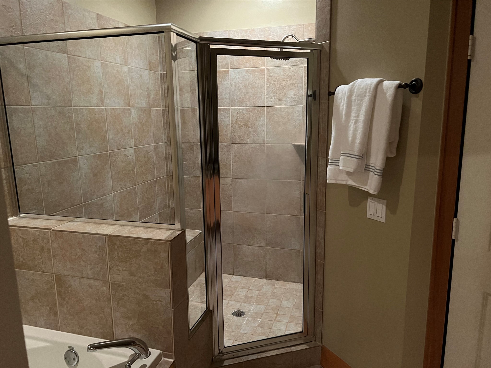 rimary bathroom features a large walk-in shower with tile surround and sitting area.