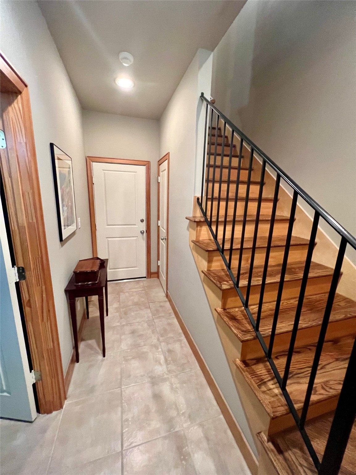 Entrance to home, tile flooring and hardwood staircase, attached 2 car garage, first floor private bedroom suite with bathroom and closet.