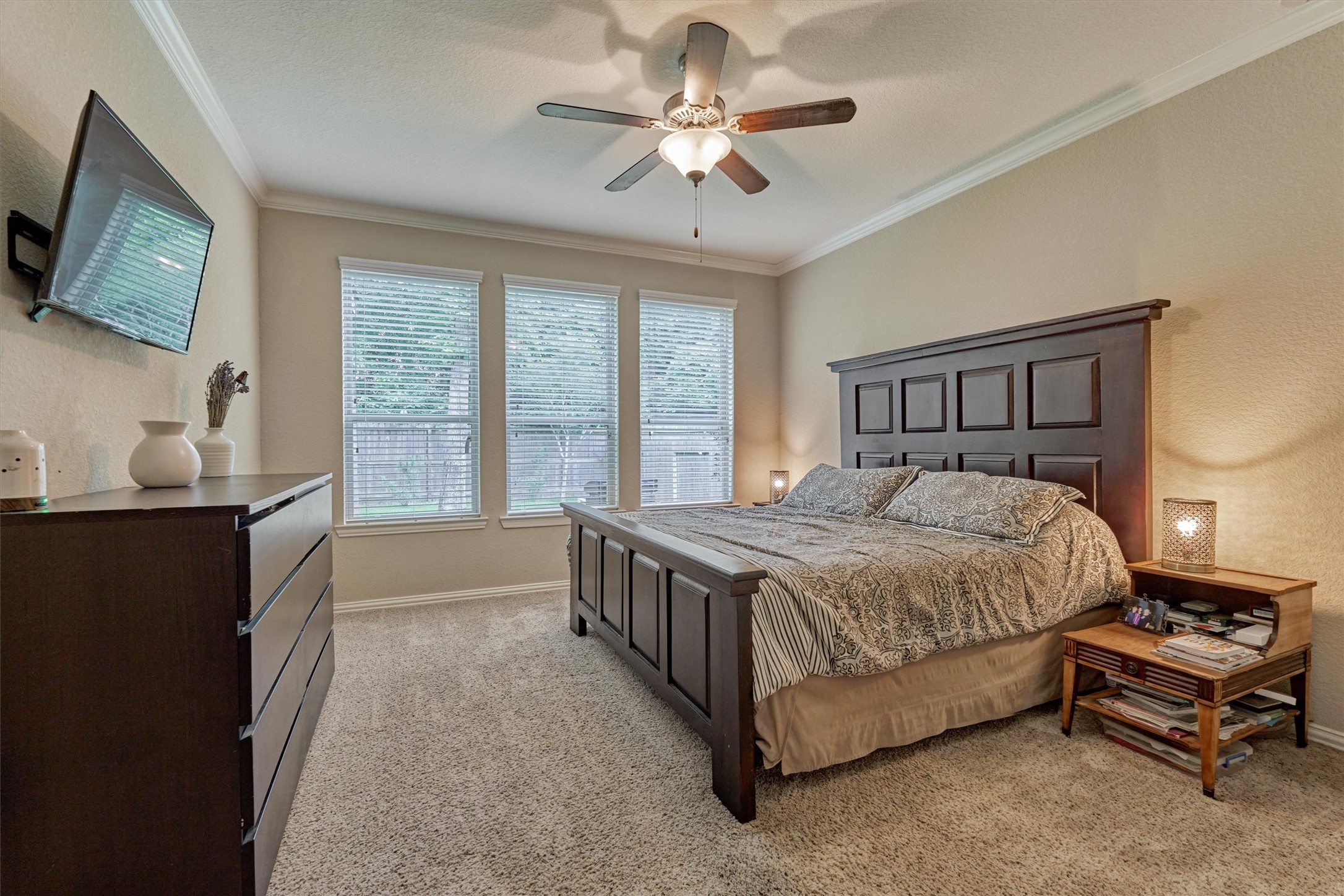 The spacious primary bedroom enjoys lovely backyard views, high end carpeted flooring, and neutral colors.
