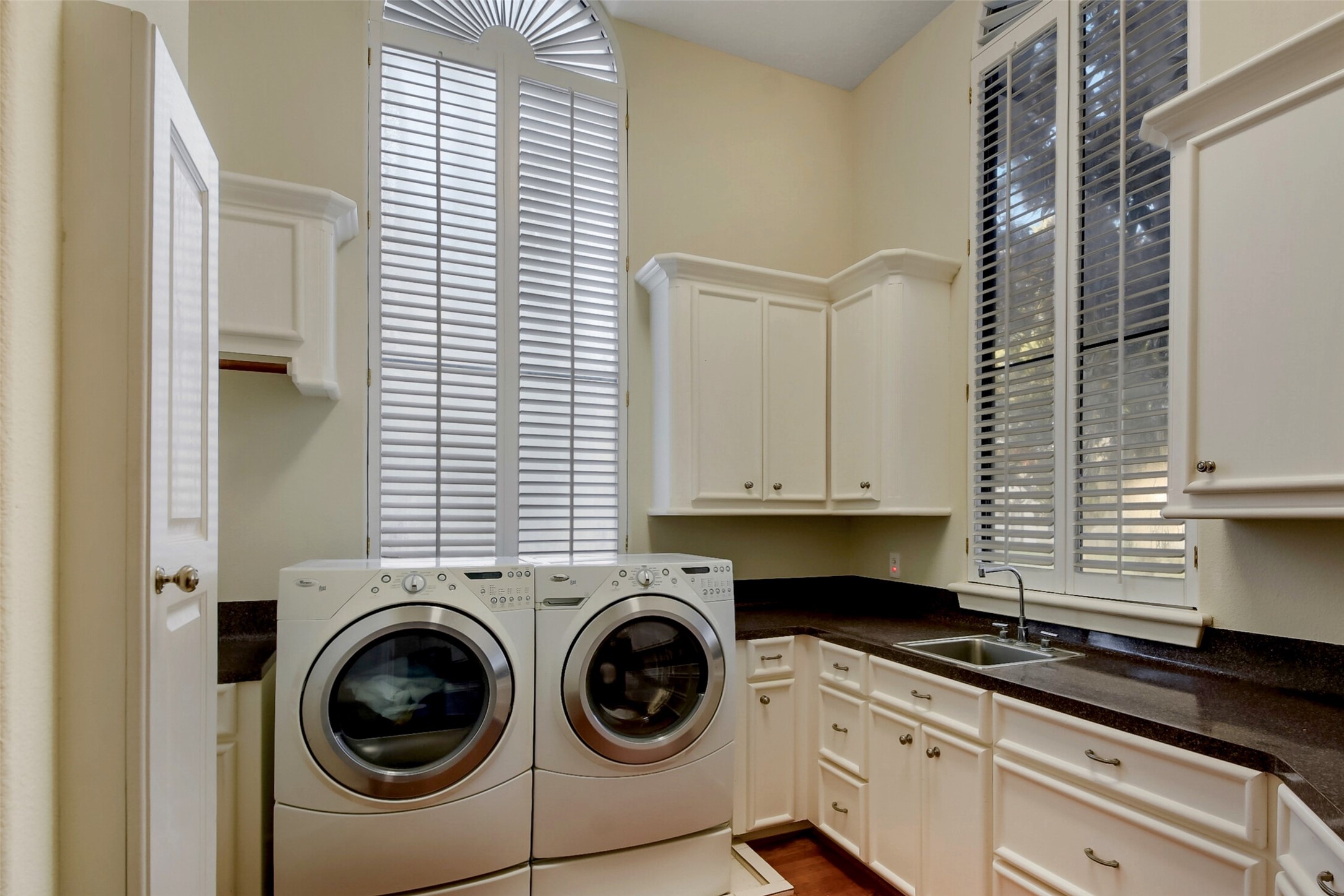 Huge laundry room with extra refrigerator, sink, plenty of counter space, and extra cabinets for storage.