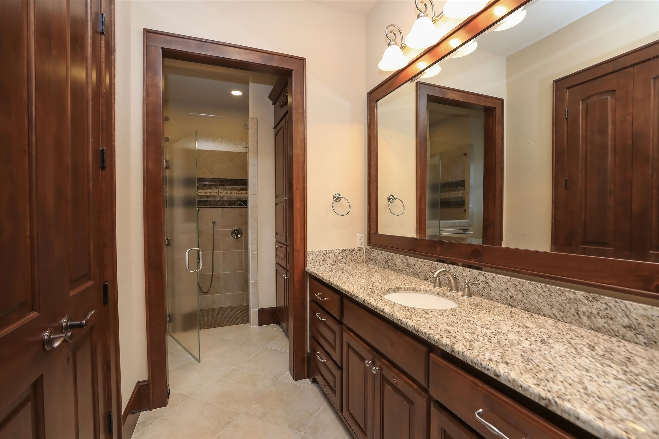 The private bathroom to the secondary bedroom has plenty of granite counter space, a walk in shower, and custom framed mirror. The doors and the cabinets throughout the house are Knotty Alder.