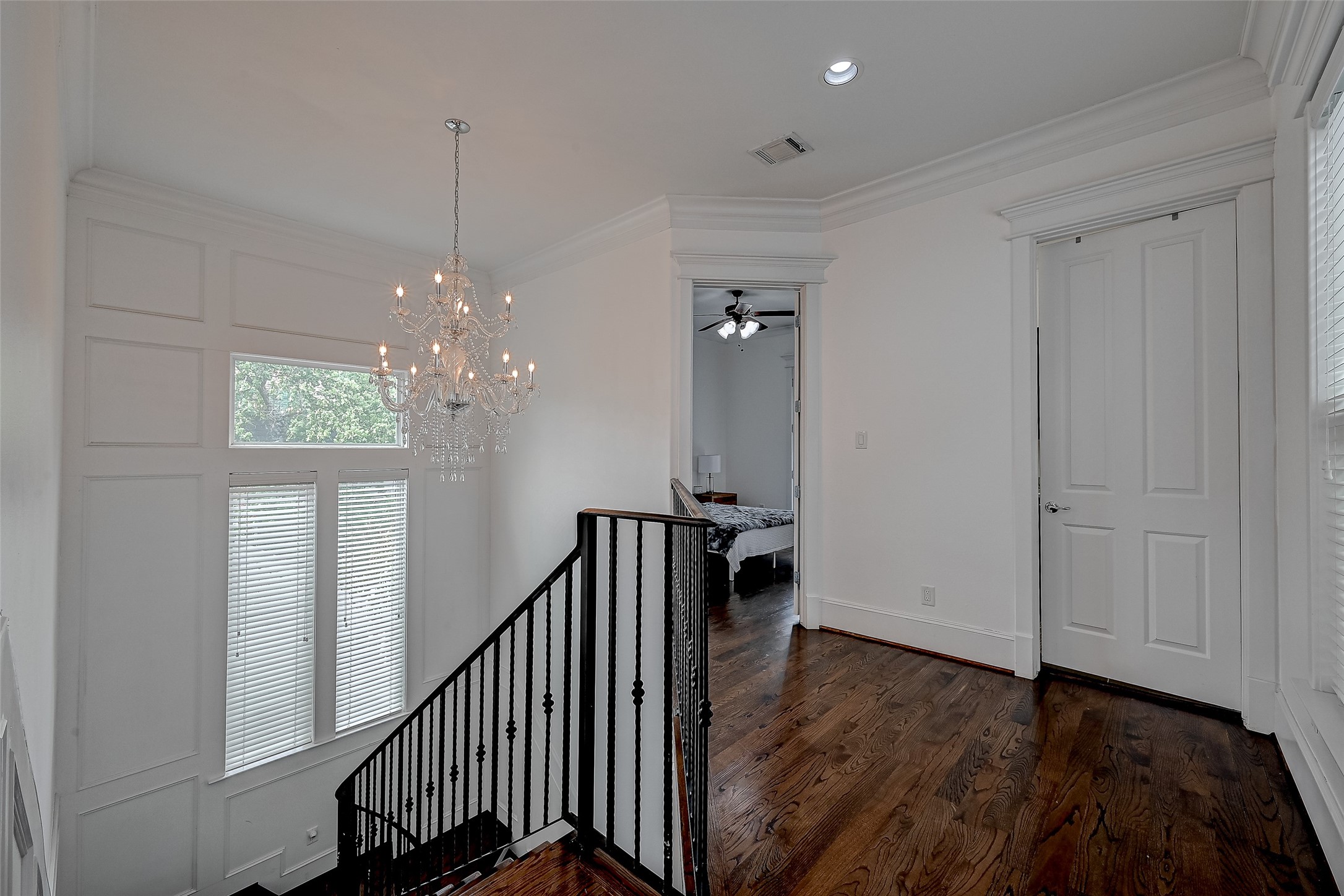 The stairway boasts elegant iron stair railings that lend an air of sophistication, accentuated by a captivating chandelier that illuminates the path with a touch of opulence. Tall windows guide the ascent, drawing in natural light, and culminate in an open second-floor landing that offers a sense of space and connection between levels.